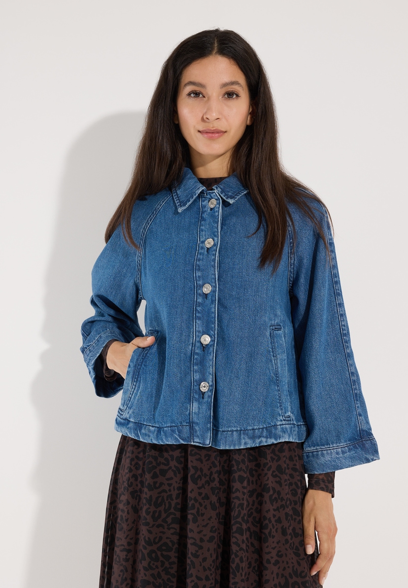 MORE & MORE Jeansjacke aus Denim mit langen Ärmeln und silbernen Knöpfen. Eine Dame trägt die Jacke über einem braun-weiß gemusterten Kleid. MORE & MORE Jeansjacke aus Denim mit langen Ärmeln und silbernen Knöpfen. Eine Dame trägt die Jacke über einem braun-weiß gemusterten Kleid.