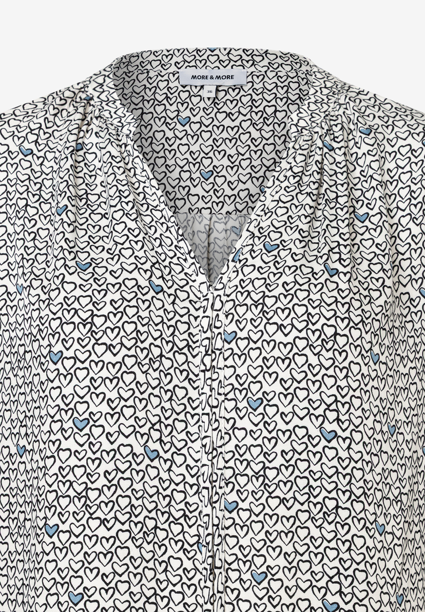 Nahaufnahme einer MORE & MORE Bluse mit Herzmuster in Schwarz, Weiß und Blau. Nahaufnahme einer MORE & MORE Bluse mit Herzmuster in Schwarz, Weiß und Blau.