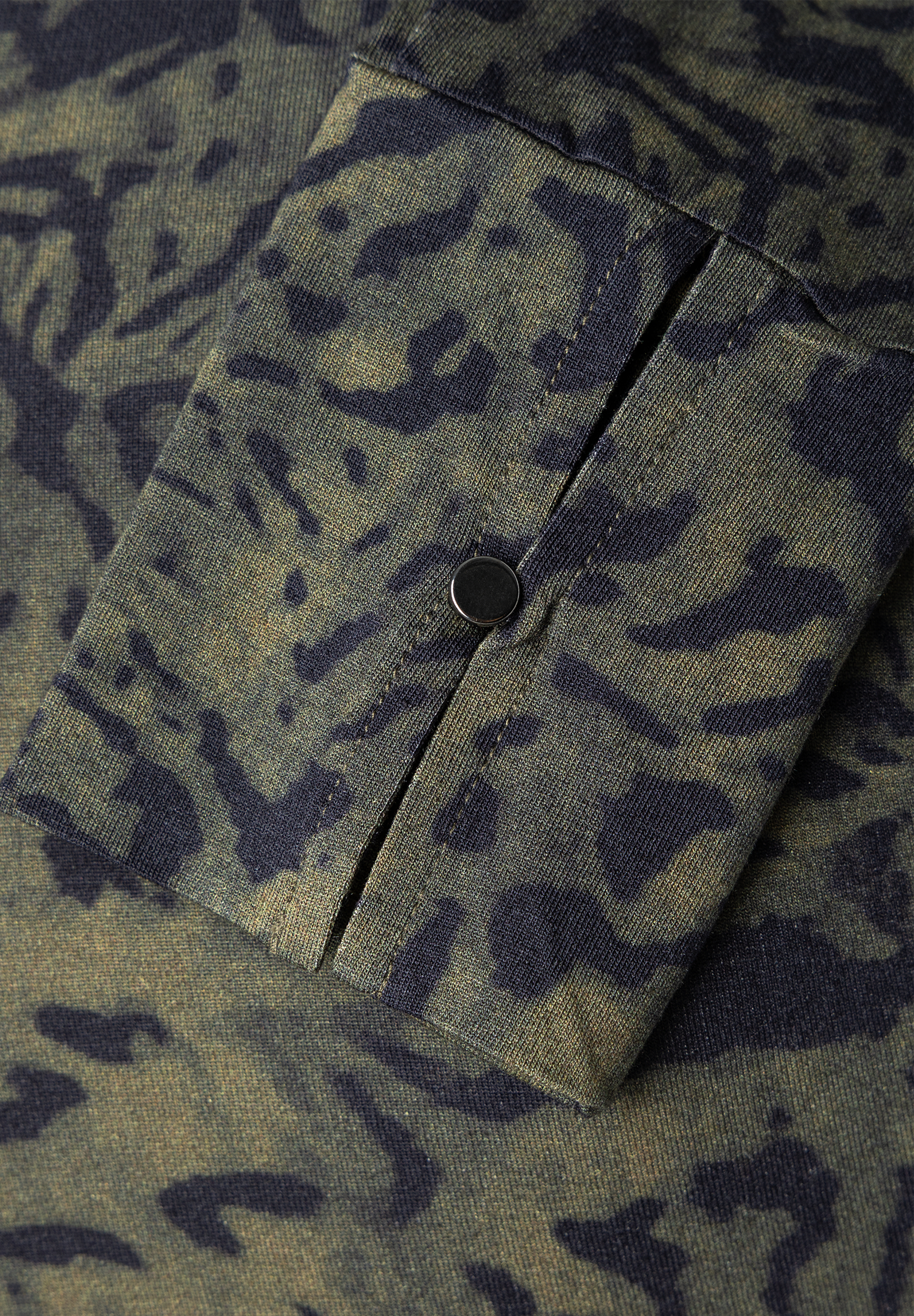 MORE & MORE T-Shirt/Top mit Leo-Muster in Khaki und Schwarz. Detailansicht eines Ärmels mit metallischem Knopf.