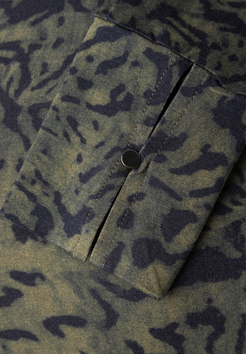 MORE & MORE T-Shirt/Top mit Leo-Muster in Khaki und Schwarz. Detailansicht eines Ärmels mit metallischem Knopf.