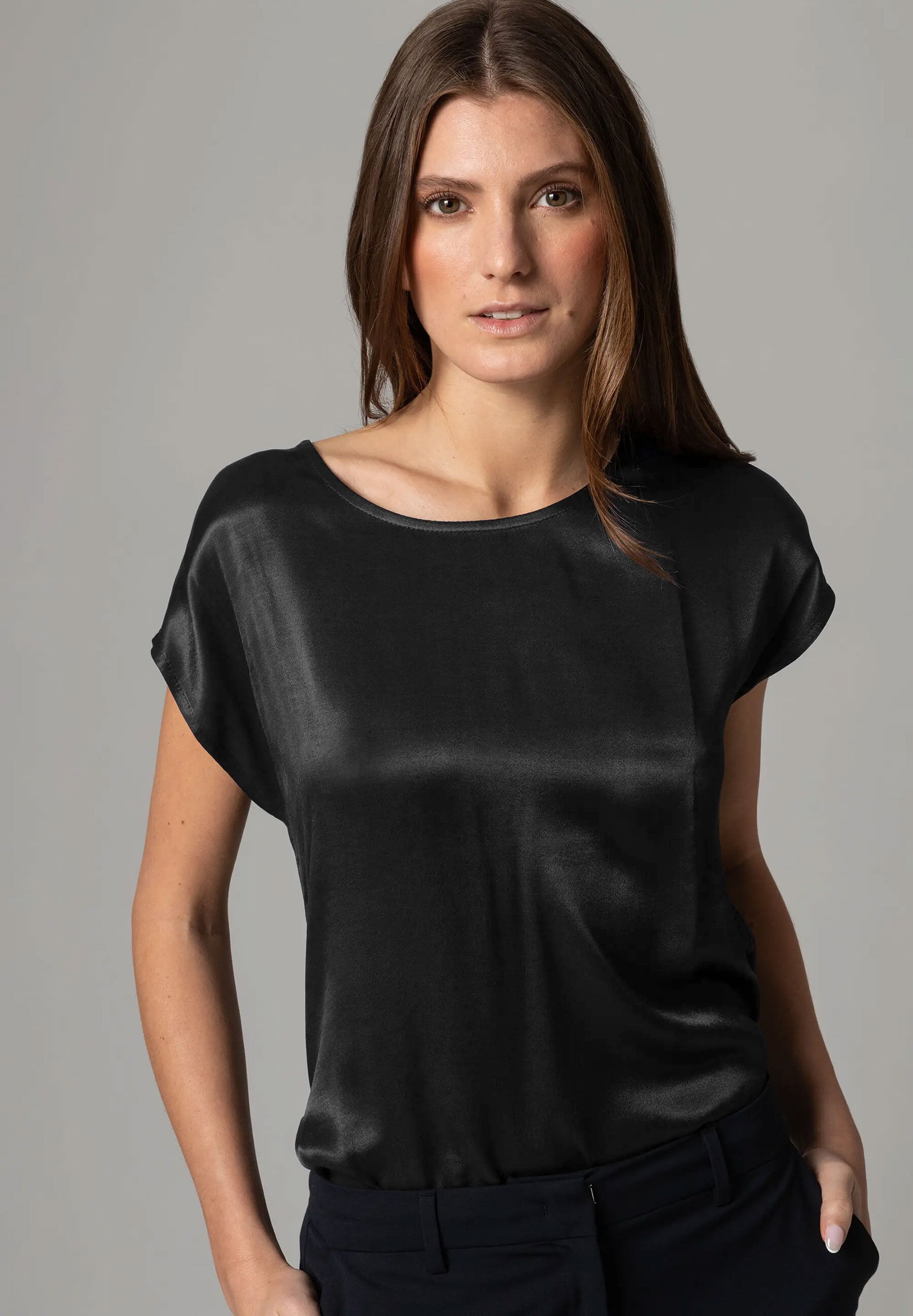 Eine Frau trägt ein schwarzes MORE & MORE Satin-Top. Es hat einen angenehmen Tragekomfort und einen seidigen Glanz. Eine Frau trägt ein schwarzes MORE & MORE Satin-Top. Es hat einen angenehmen Tragekomfort und einen seidigen Glanz.