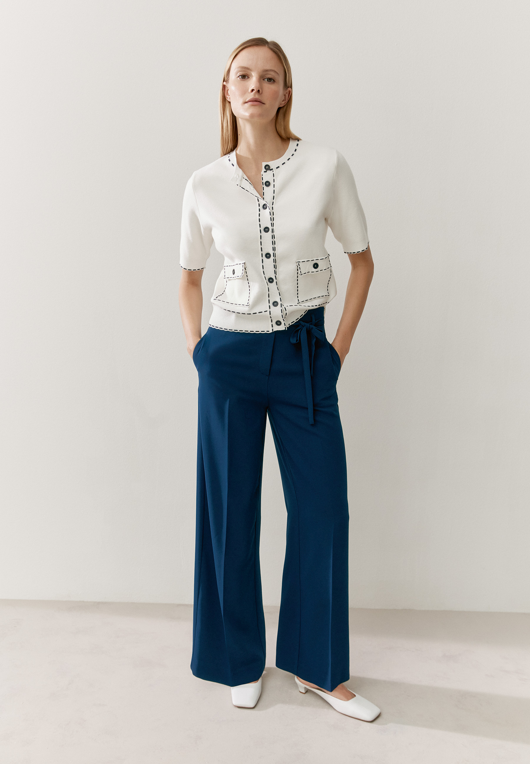 Eine Frau mit MORE & MORE Strick-Oberteil mit Ziernähten und blauer Hose. Eine Frau mit MORE & MORE Strick-Oberteil mit Ziernähten und blauer Hose.