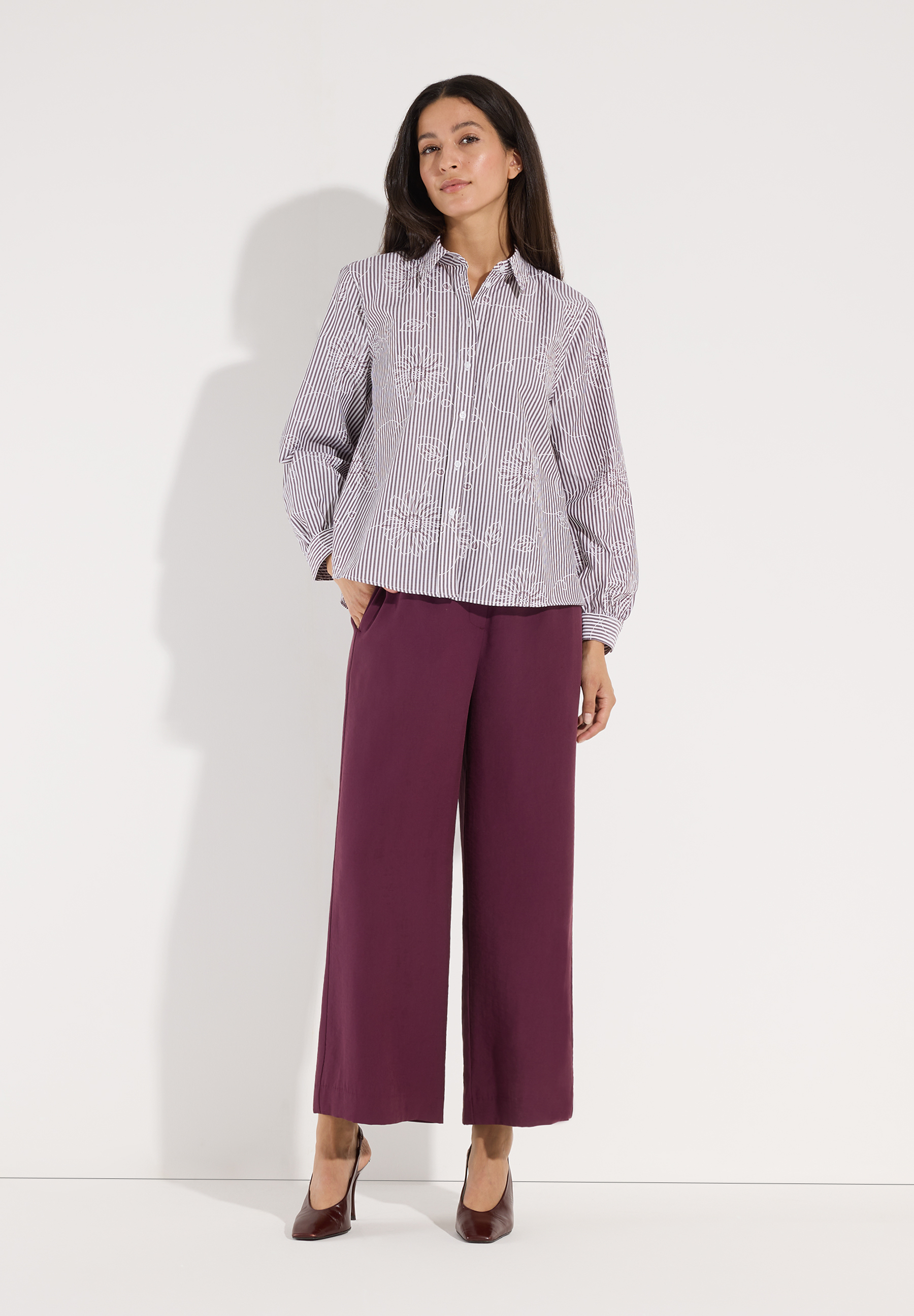 MORE & MORE Bluse: Gestreiftes Oberteil mit floraler Stickerei auf einer Frau, die weinrote Hose und braune Schuhe trägt. MORE & MORE Bluse: Gestreiftes Oberteil mit floraler Stickerei auf einer Frau, die weinrote Hose und braune Schuhe trägt.