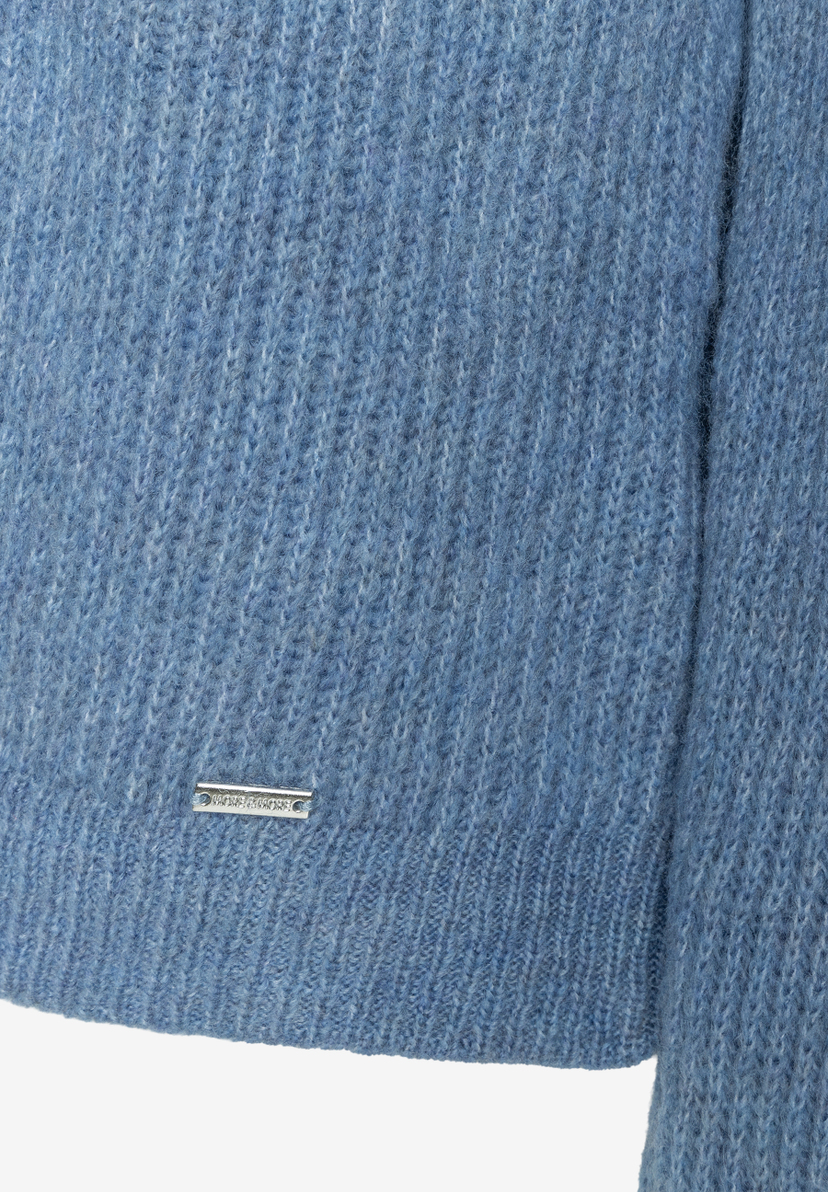 MORE & MORE Pullover/Strickwaren: Detail eines himmelblauen, gestrickten Stoffes, mit Metall-Label MORE & MORE Pullover/Strickwaren: Detail eines himmelblauen, gestrickten Stoffes, mit Metall-Label