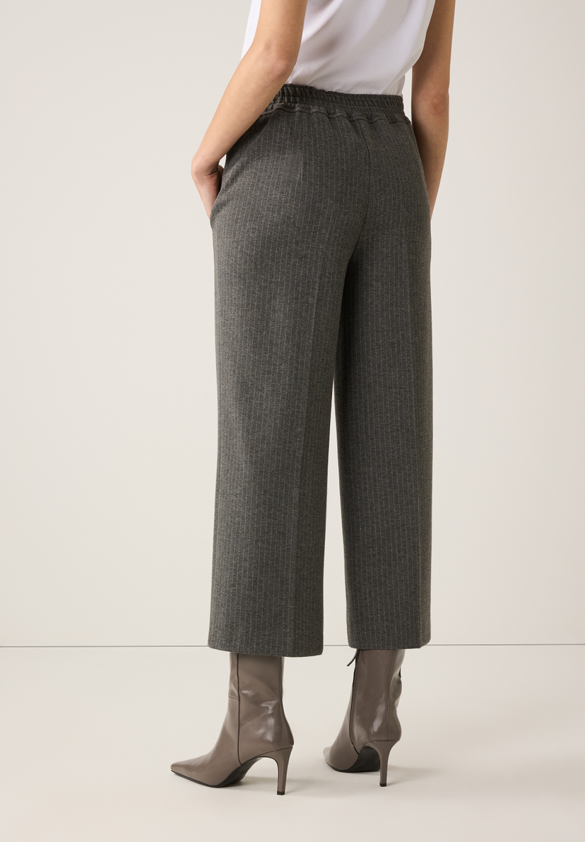 Die MORE & MORE Hose ist grau-meliert und knöchellang. Dazu werden graue Stiefeletten getragen. Die MORE & MORE Hose ist grau-meliert und knöchellang. Dazu werden graue Stiefeletten getragen.