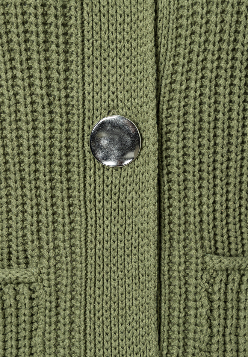 Nahaufnahme einer grünen MORE & MORE Strickjacke mit silberfarbenem Knopf und Rippstrick-Muster. Nahaufnahme einer grünen MORE & MORE Strickjacke mit silberfarbenem Knopf und Rippstrick-Muster.