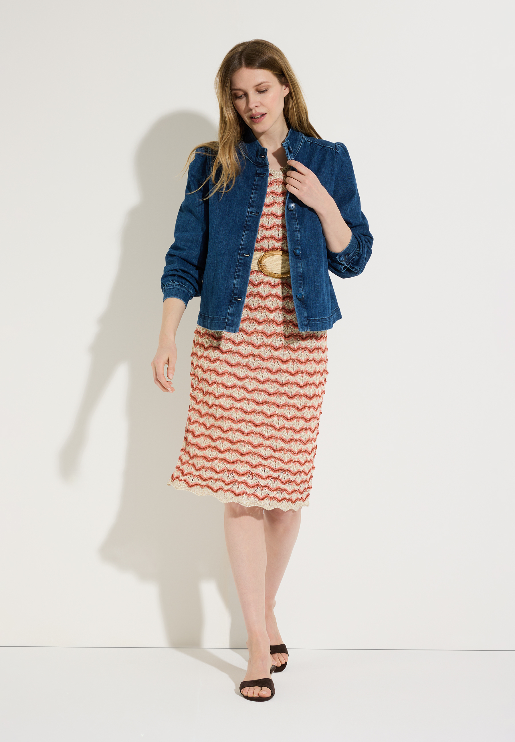 Eine Frau trägt einen MORE & MORE Blazer aus Denim über einem Kleid mit Zickzackmuster. Eine Frau trägt einen MORE & MORE Blazer aus Denim über einem Kleid mit Zickzackmuster.