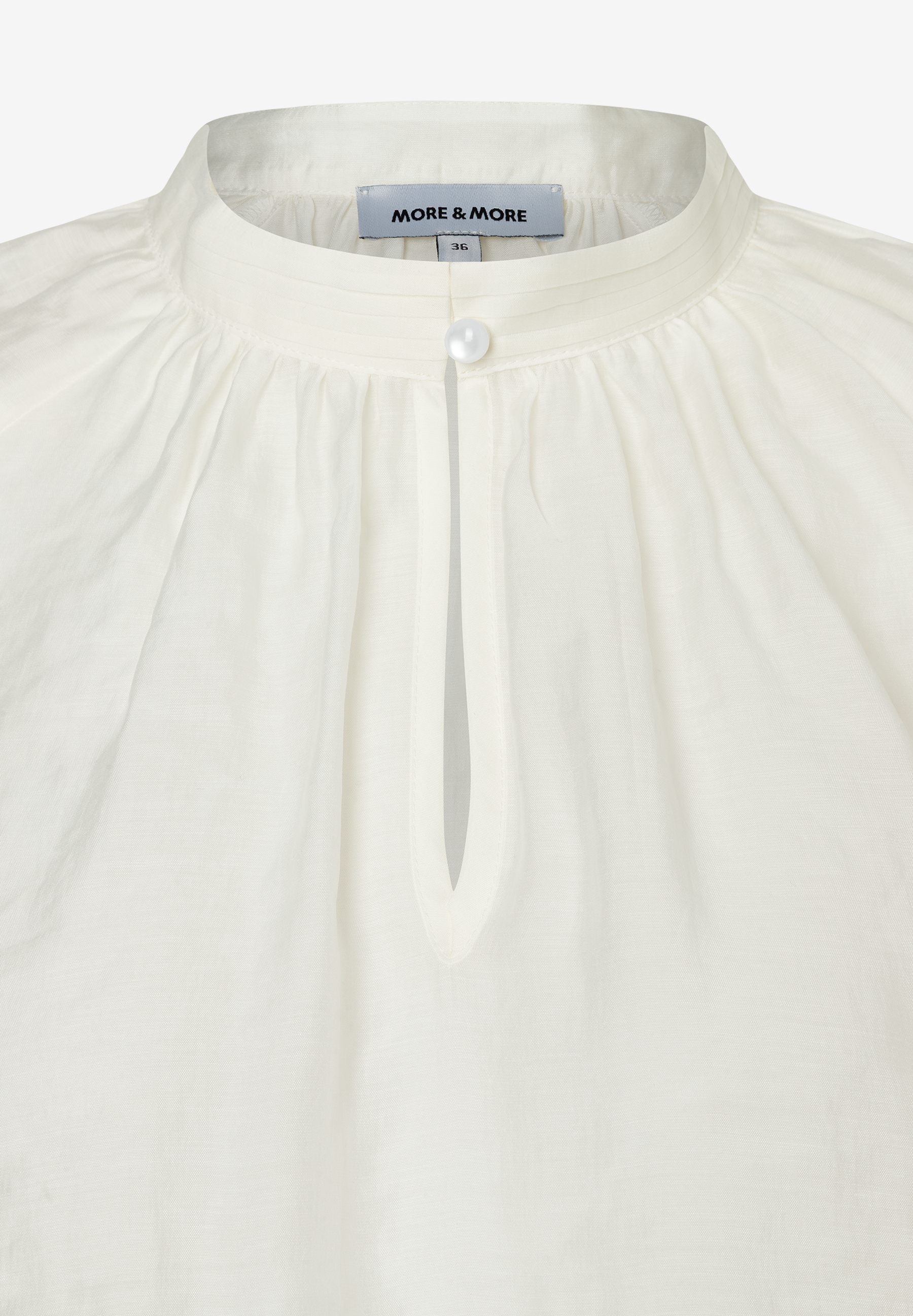 Nahaufnahme einer weißen MORE & MORE Bluse mit Stehkragen und Knopf. Nahaufnahme einer weißen MORE & MORE Bluse mit Stehkragen und Knopf.
