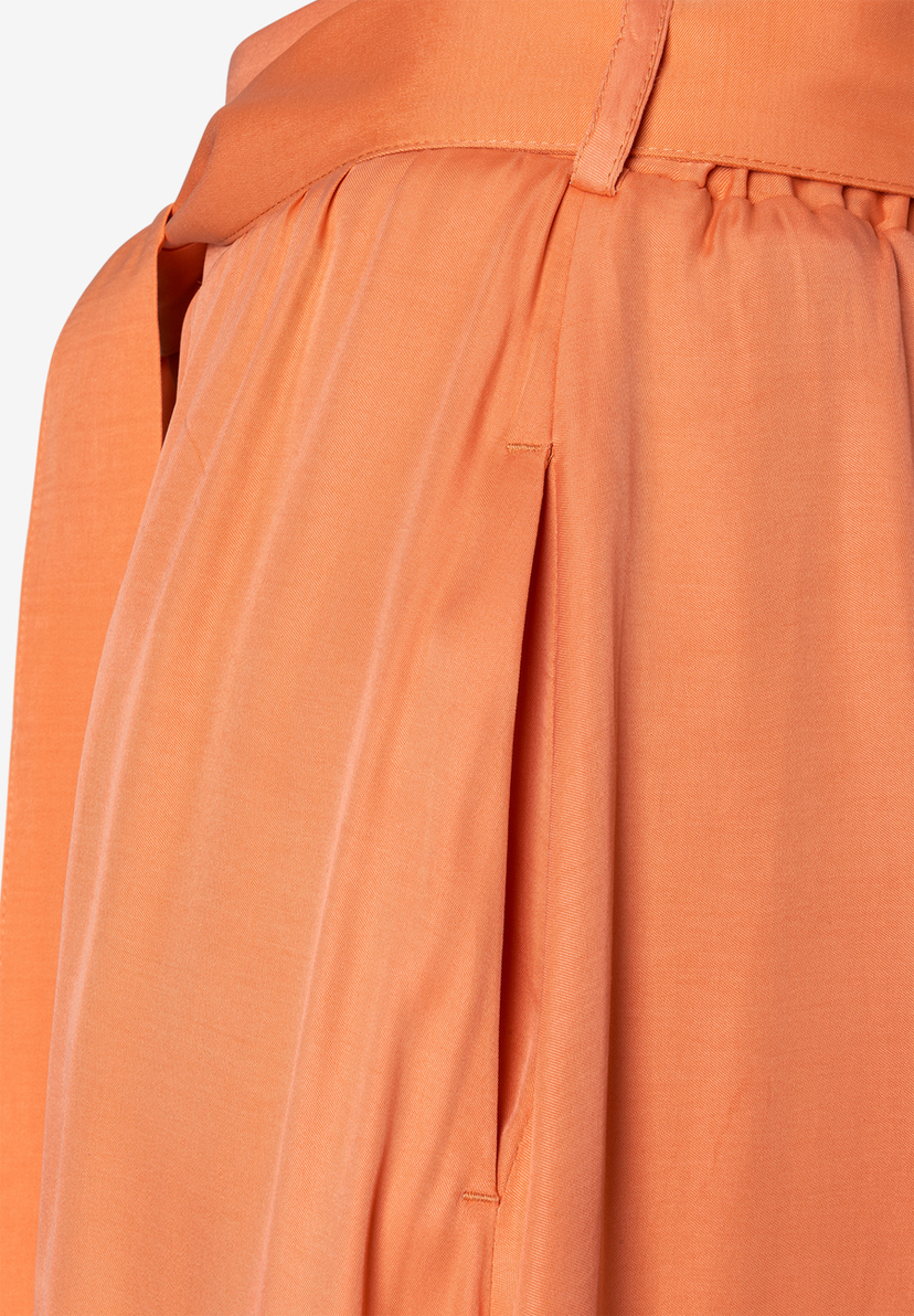 Detailansicht eines apricotfarbenen Viskose-Rocks von MORE & MORE mit fließendem Fall und seitlicher Eingrifftasche.