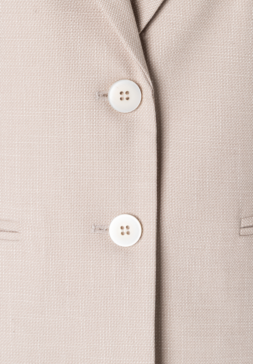 Nahaufnahme eines MORE & MORE Blazers mit zwei Knöpfen und Webware-Struktur. Nahaufnahme eines MORE & MORE Blazers mit zwei Knöpfen und Webware-Struktur.
