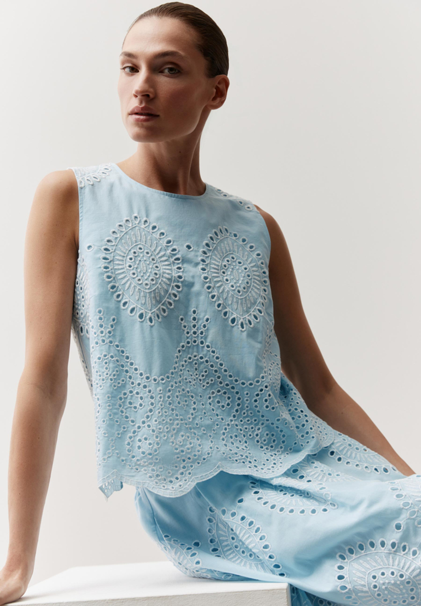Eine hellblaue MORE & MORE Bluse mit feiner Lochstickerei an Kragen, Ärmeln und Saum, betont durch ein helles, freundliches Licht. Eine hellblaue MORE & MORE Bluse mit feiner Lochstickerei an Kragen, Ärmeln und Saum, betont durch ein helles, freundliches Licht.
