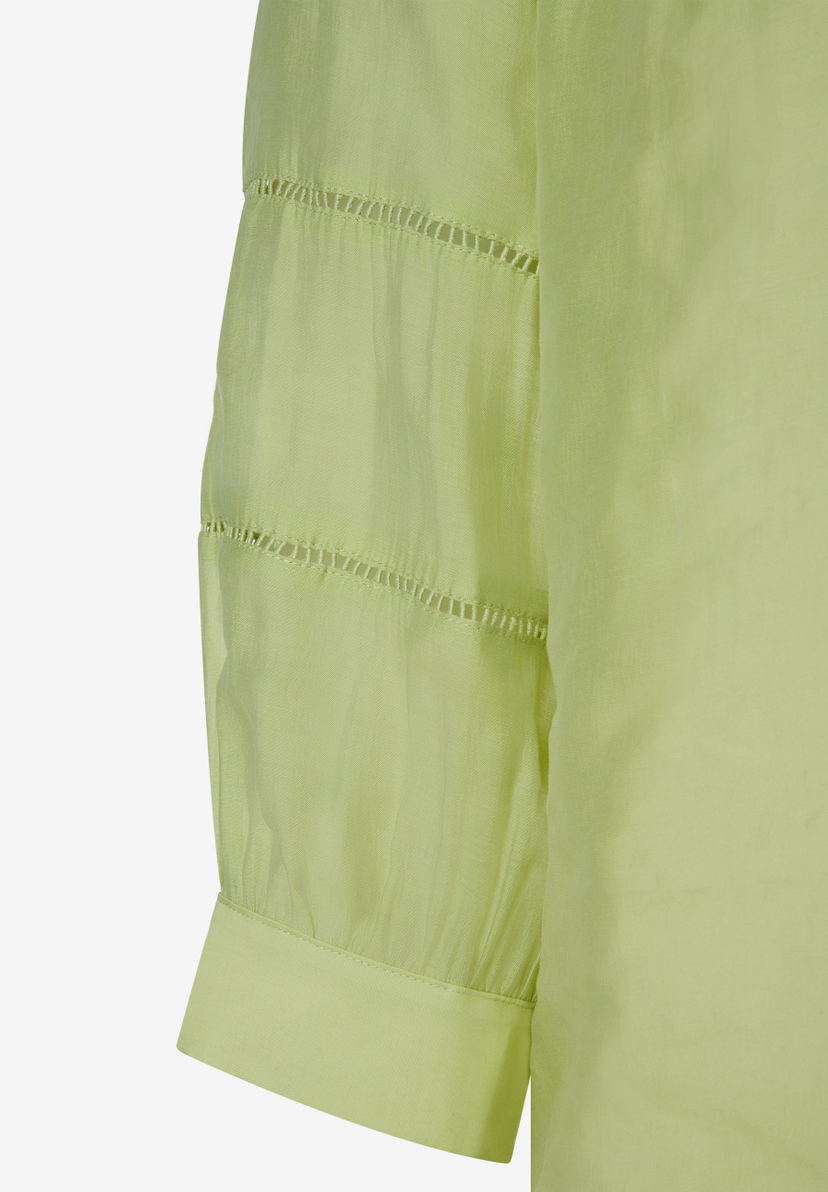 Nahaufnahme einer hellgrünen, leicht transparenten MORE & MORE Bluse mit kurzen Ärmeln und Lochstickerei. Nahaufnahme einer hellgrünen, leicht transparenten MORE & MORE Bluse mit kurzen Ärmeln und Lochstickerei.