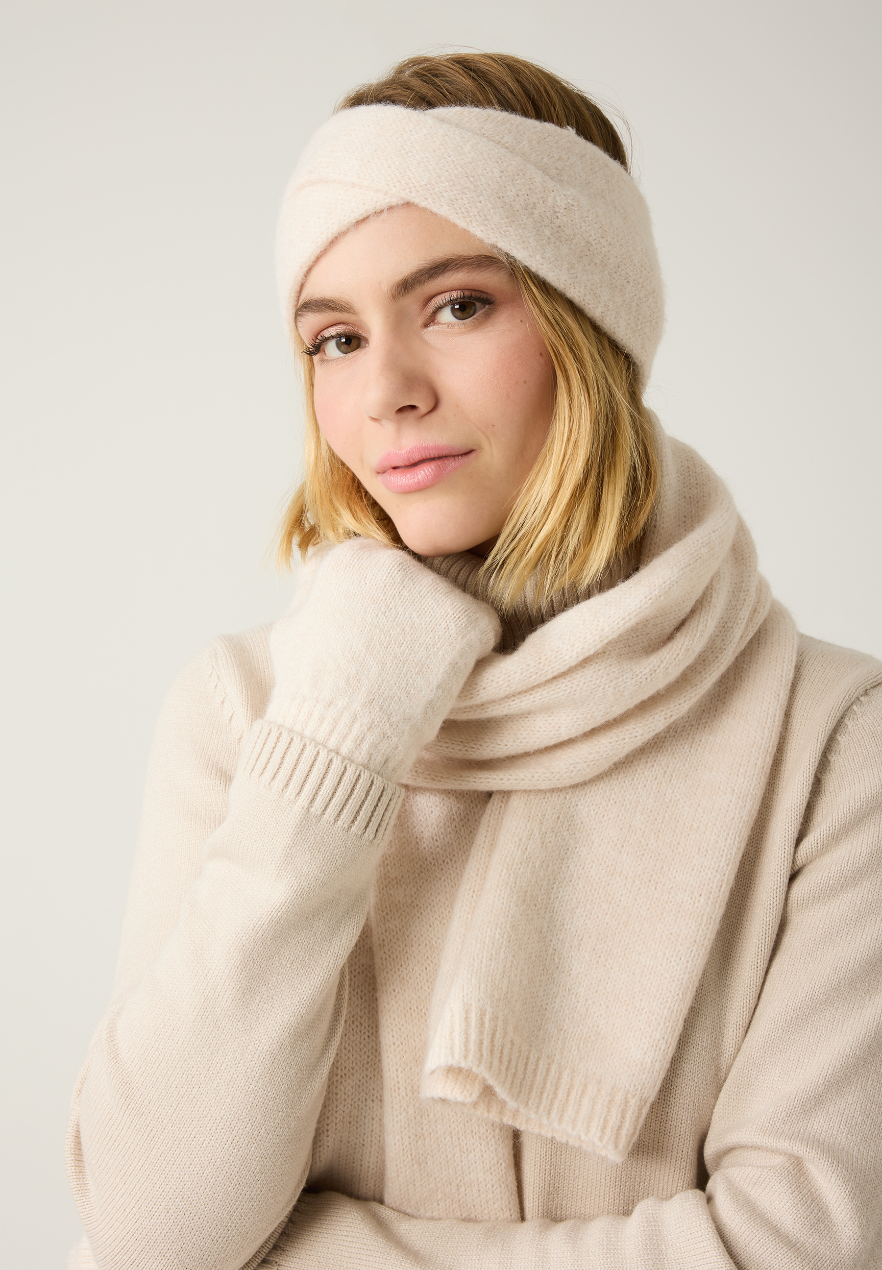 Eine Frau mit blonden Haaren, MORE & MORE Accessoires, Handschuhe, Stirnband und Schal in Beige.