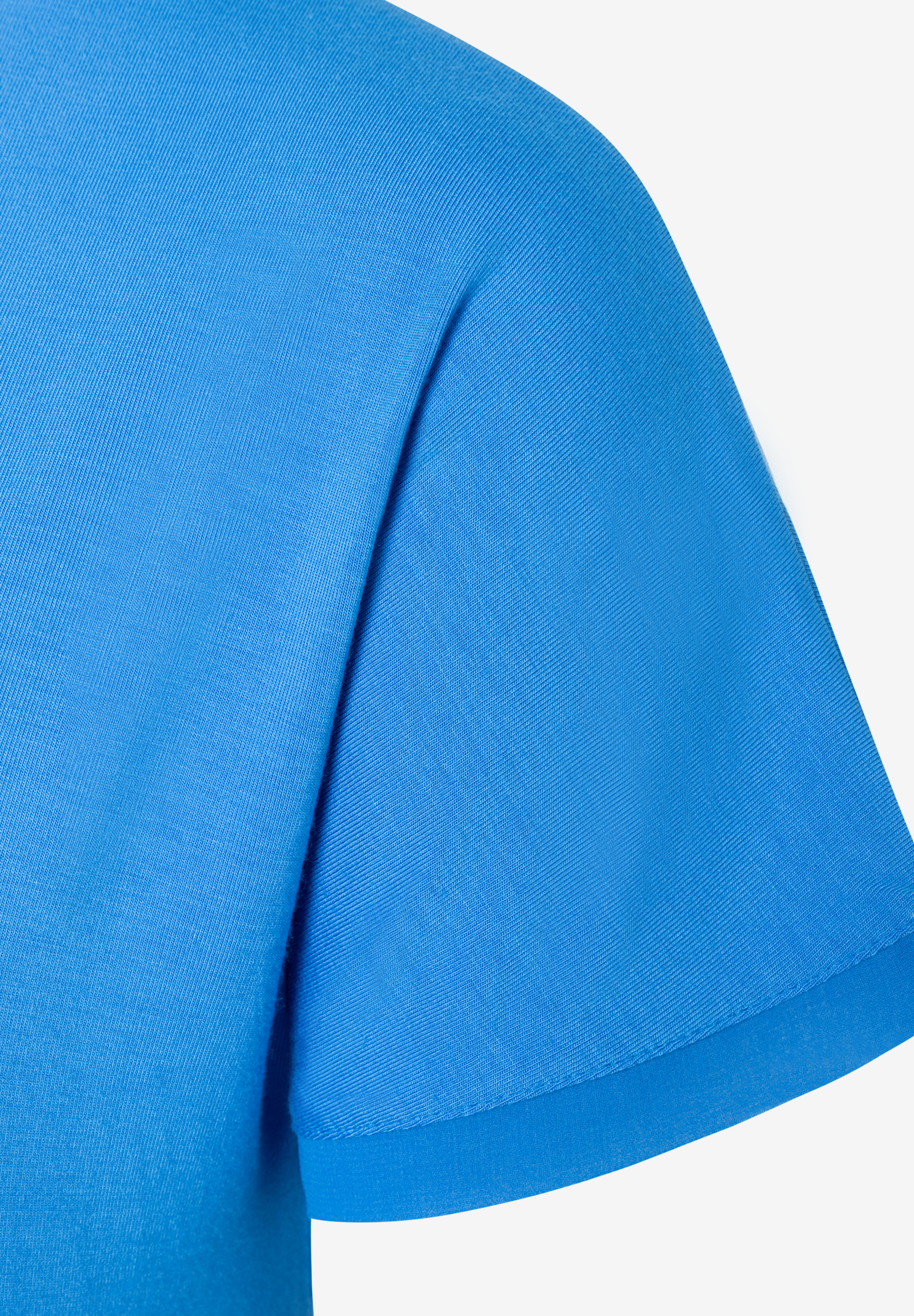 MORE & MORE T-Shirt aus elastischem Jersey in leuchtendem Blau, Nahaufnahme vom Arm und Ärmelbereich. MORE & MORE T-Shirt aus elastischem Jersey in leuchtendem Blau, Nahaufnahme vom Arm und Ärmelbereich.