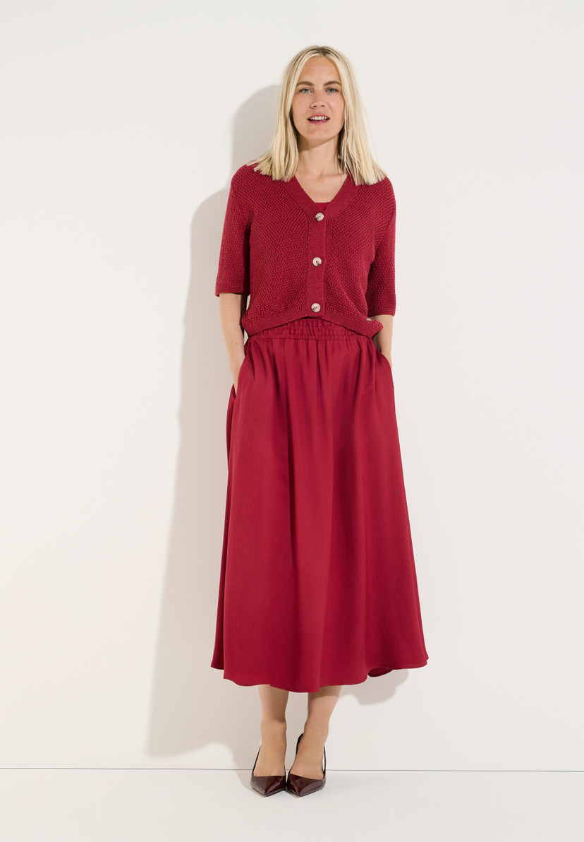 MORE & MORE Midirock in Rot mit einem passenden, kurzärmeligen Strickpullover. Die blonde Frau trägt dazu elegante, dunkelrote Pumps. MORE & MORE Midirock in Rot mit einem passenden, kurzärmeligen Strickpullover. Die blonde Frau trägt dazu elegante, dunkelrote Pumps.