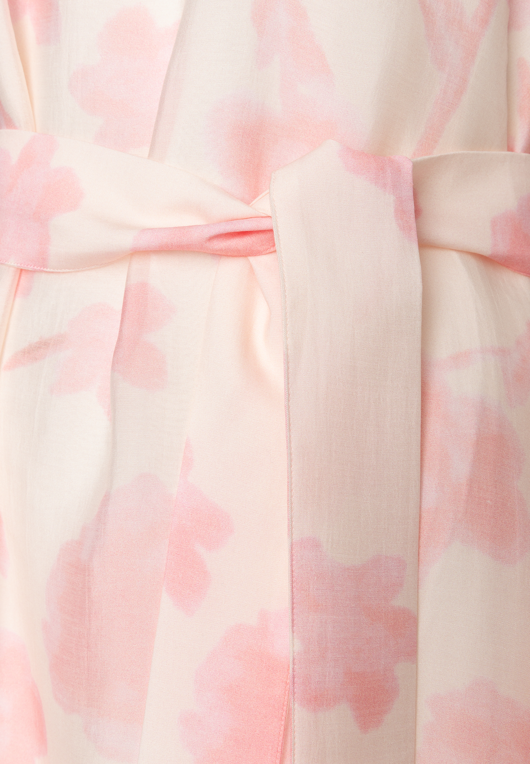 Detailansicht eines MORE & MORE Oberteils aus Chiffon mit rosa Blumenmuster und Taillenband, das für angenehmen Tragekomfort sorgt. Detailansicht eines MORE & MORE Oberteils aus Chiffon mit rosa Blumenmuster und Taillenband, das für angenehmen Tragekomfort sorgt.