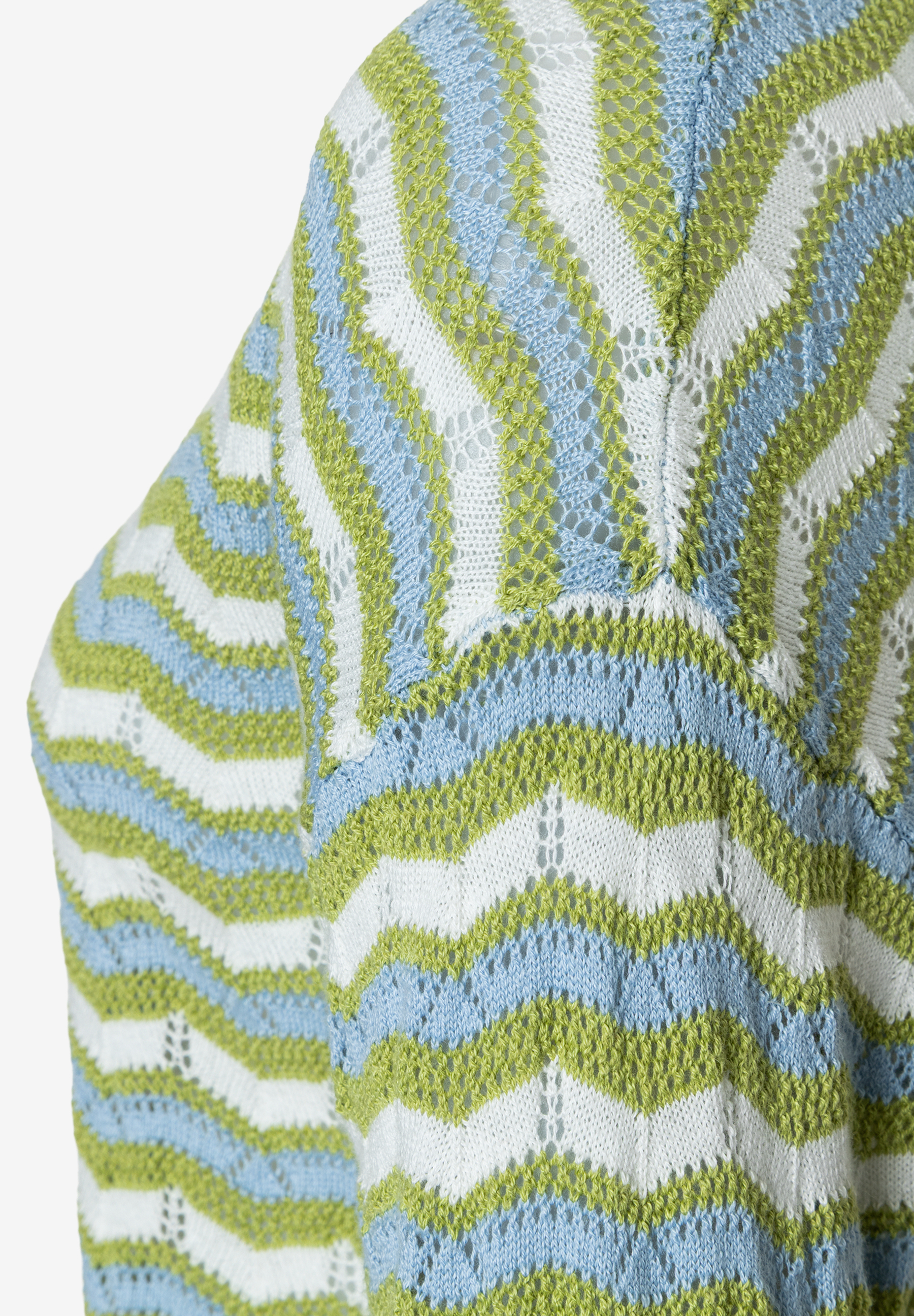 Detailaufnahme eines MORE & MORE Lochstrick-Pullovers mit blau-grün-weißem Zickzackmuster. Detailaufnahme eines MORE & MORE Lochstrick-Pullovers mit blau-grün-weißem Zickzackmuster.