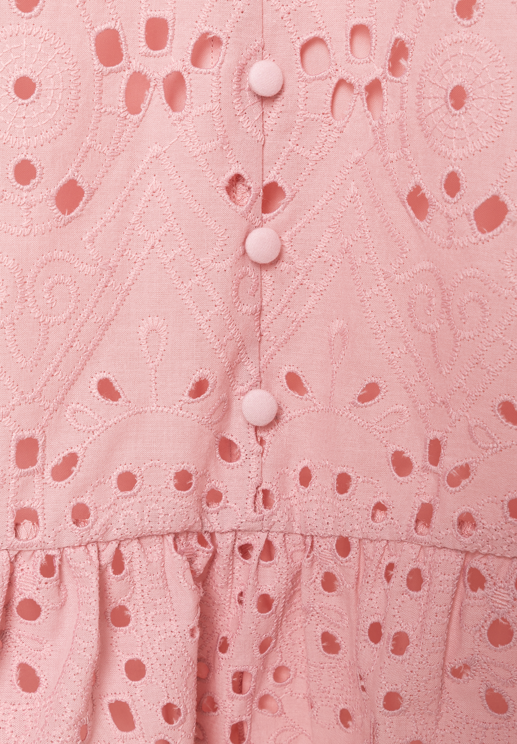 Nahaufnahme eines rosa MORE & MORE Oberteils mit Lochstickerei und Knopfleiste. Nahaufnahme eines rosa MORE & MORE Oberteils mit Lochstickerei und Knopfleiste.