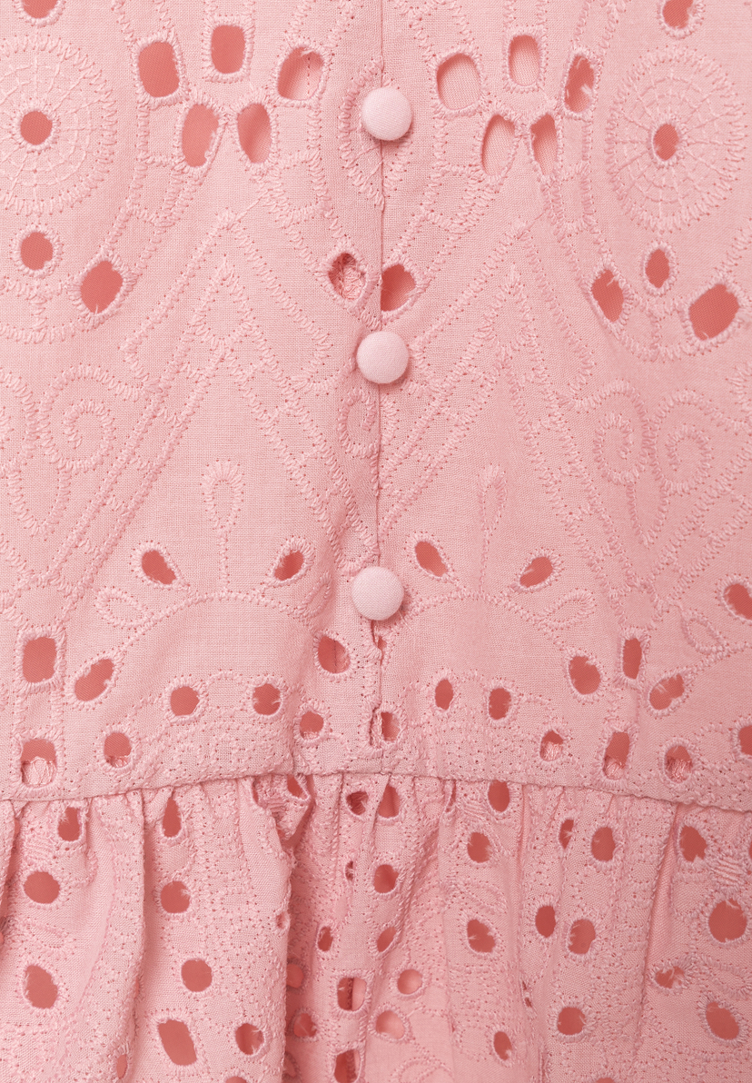 Nahaufnahme eines rosa MORE & MORE Oberteils mit Lochstickerei und Knopfleiste. Nahaufnahme eines rosa MORE & MORE Oberteils mit Lochstickerei und Knopfleiste.