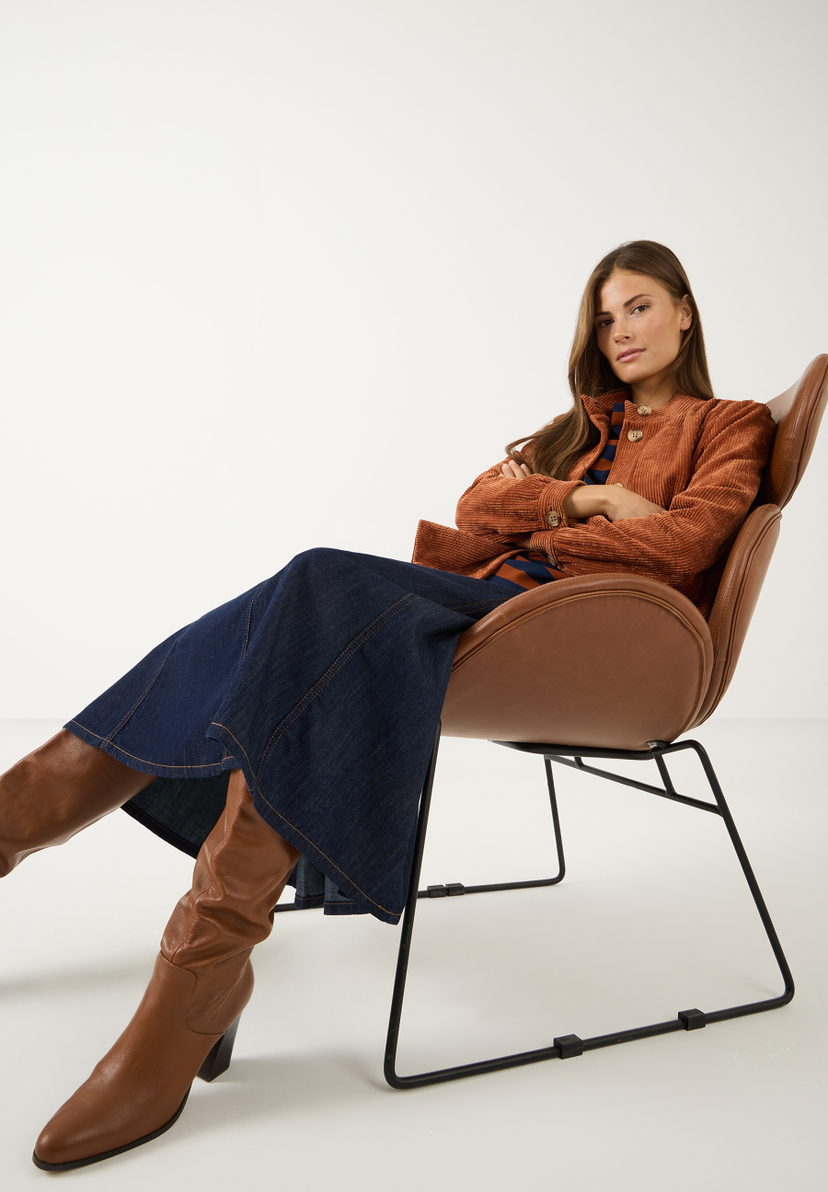 MORE & MORE Cordjacke in Rostbraun und blau-weiß gestreiftes Shirt. Model sitzt lässig in cognacfarbenem Ledersessel. MORE & MORE Cordjacke in Rostbraun und blau-weiß gestreiftes Shirt. Model sitzt lässig in cognacfarbenem Ledersessel.