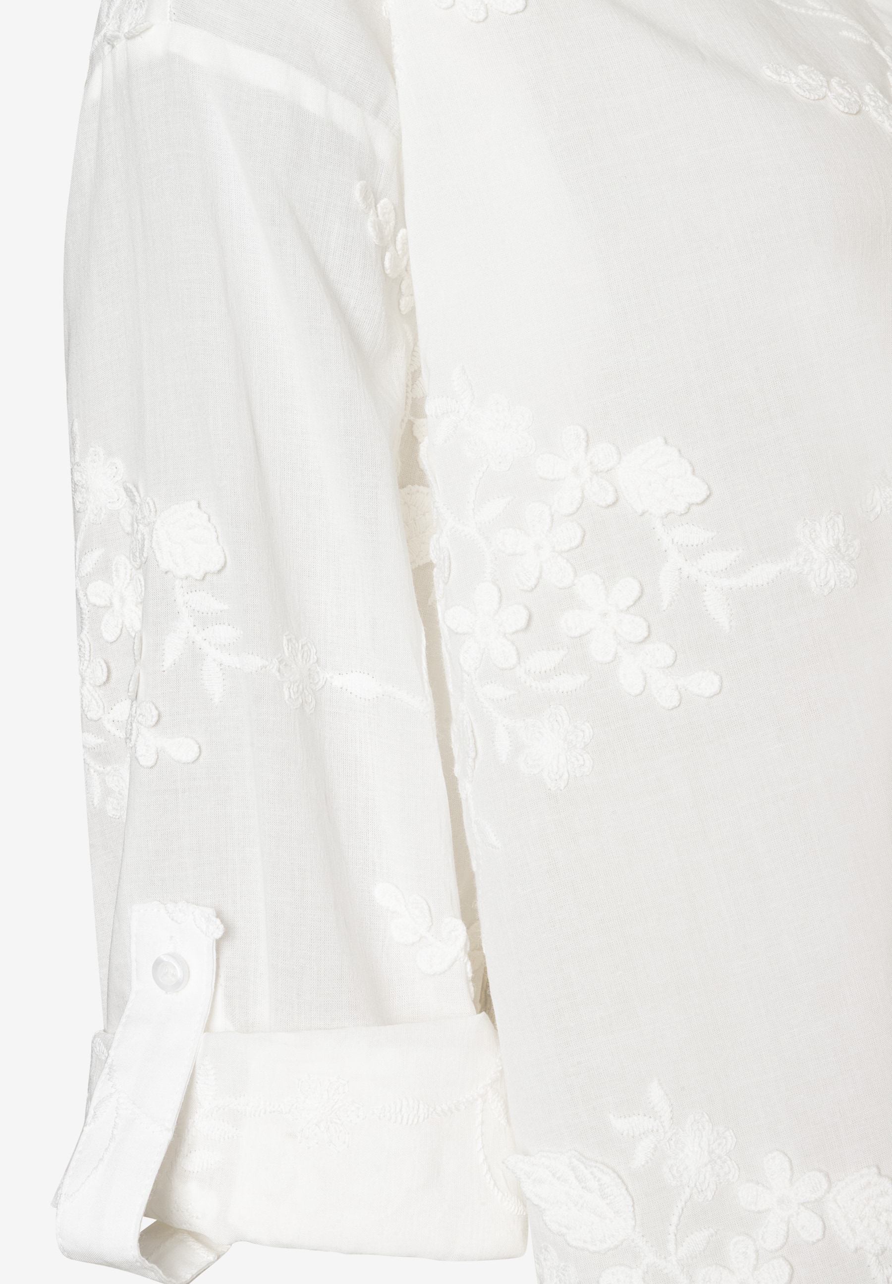 Detailaufnahme einer weißen MORE & MORE Bluse mit floralen Stickereien am Ärmel und Manschetten. Detailaufnahme einer weißen MORE & MORE Bluse mit floralen Stickereien am Ärmel und Manschetten.