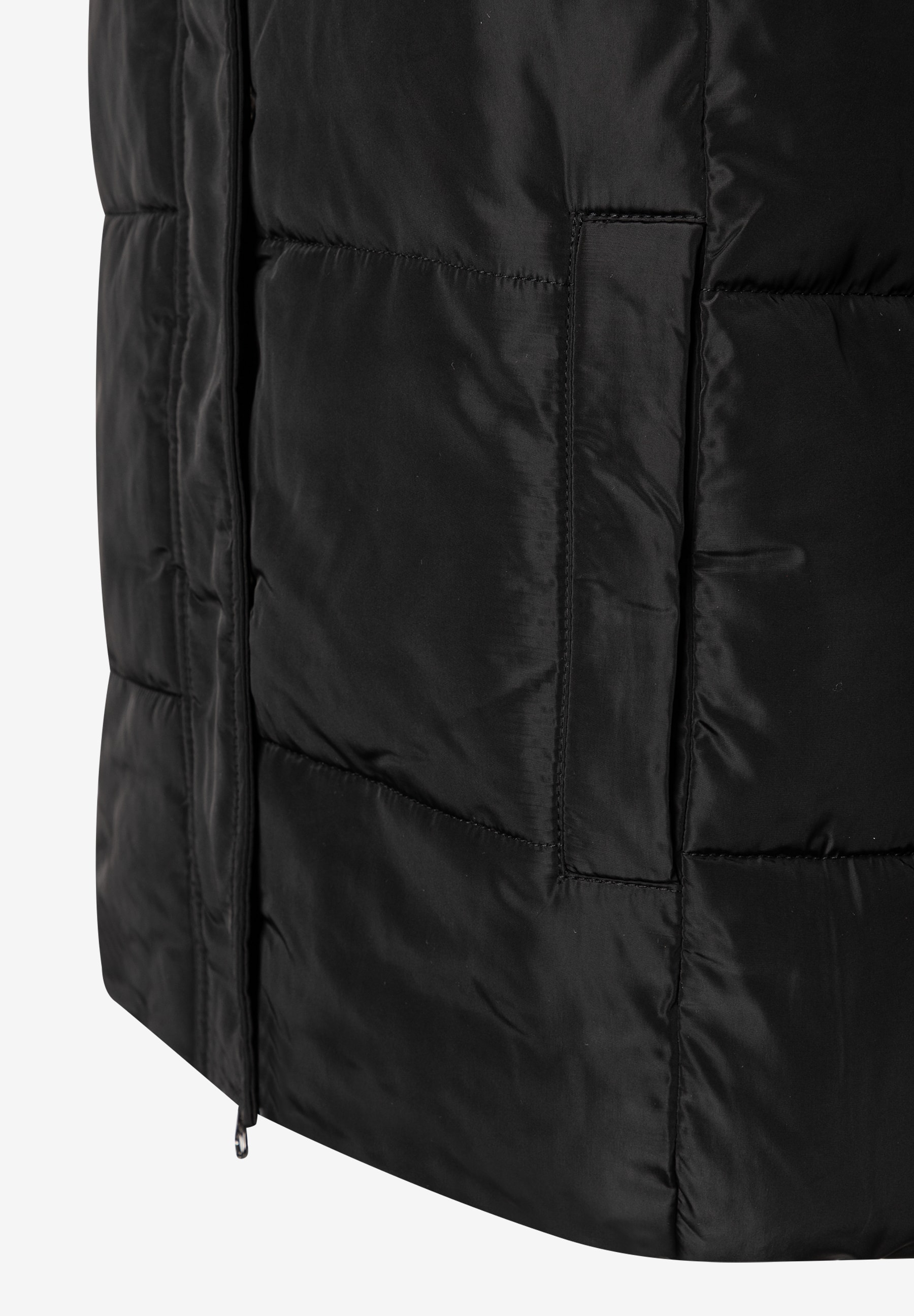 Detailaufnahme eines schwarzen MORE & MORE Oberteils mit gestepptem Design und diskretem Reißverschluss. Detailaufnahme eines schwarzen MORE & MORE Oberteils mit gestepptem Design und diskretem Reißverschluss.