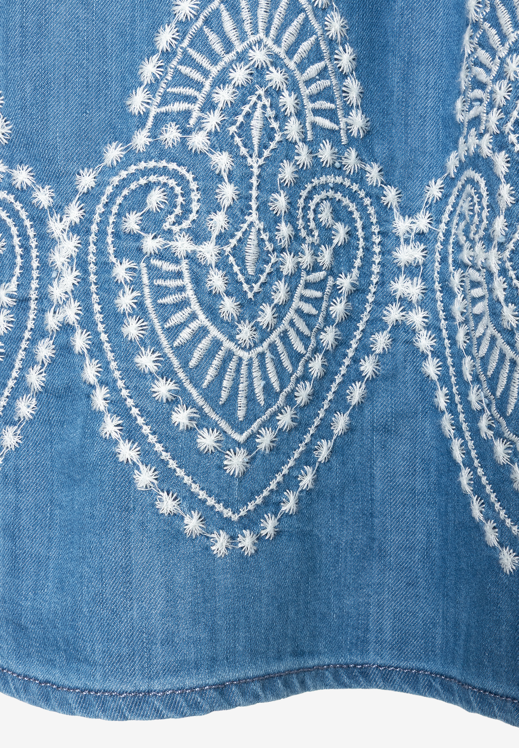 Detailaufnahme eines MORE & MORE Jeansrocks mit dekorativer, weißer Herzstickerei. Detailaufnahme eines MORE & MORE Jeansrocks mit dekorativer, weißer Herzstickerei.