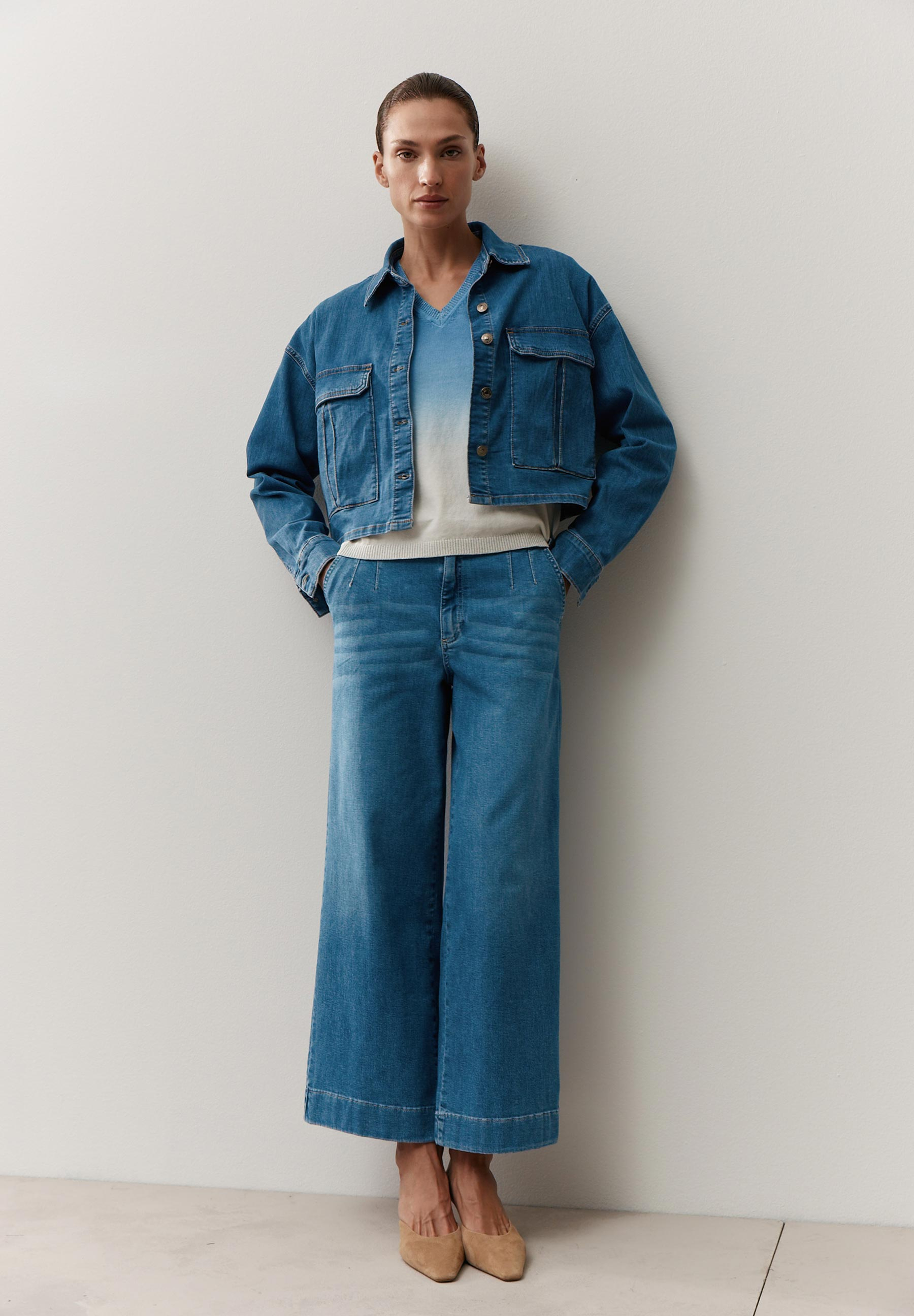 Eine Frau in Denim-Jacke und Wide-Leg-Jeans von MORE & MORE. Darunter trägt sie einen Pullover-Knitwear-Artikel. Eine Frau in Denim-Jacke und Wide-Leg-Jeans von MORE & MORE. Darunter trägt sie einen Pullover-Knitwear-Artikel.