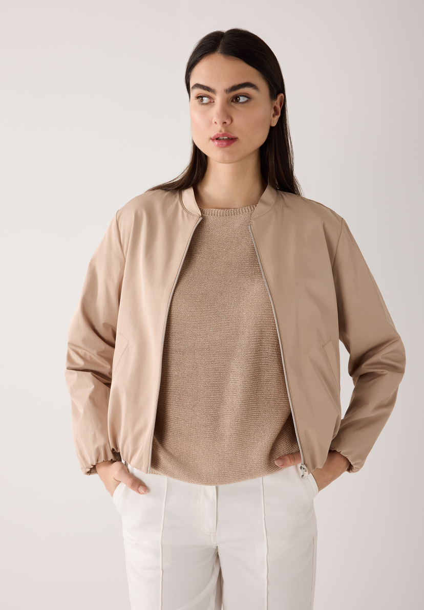 Eine Frau trägt eine MORE & MORE Jacke aus Webware. Sie hat dazu einen grauen Rock und ein graues Rollkragenshirt an. Eine Frau trägt eine MORE & MORE Jacke aus Webware. Sie hat dazu einen grauen Rock und ein graues Rollkragenshirt an.
