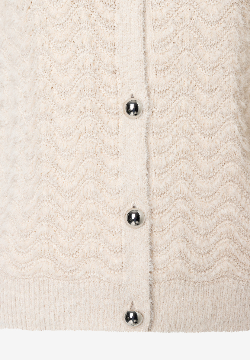 Nahaufnahme eines MORE & MORE Oberteils in Strukturstrick mit silbernen Knöpfen. Nahaufnahme eines MORE & MORE Oberteils in Strukturstrick mit silbernen Knöpfen.