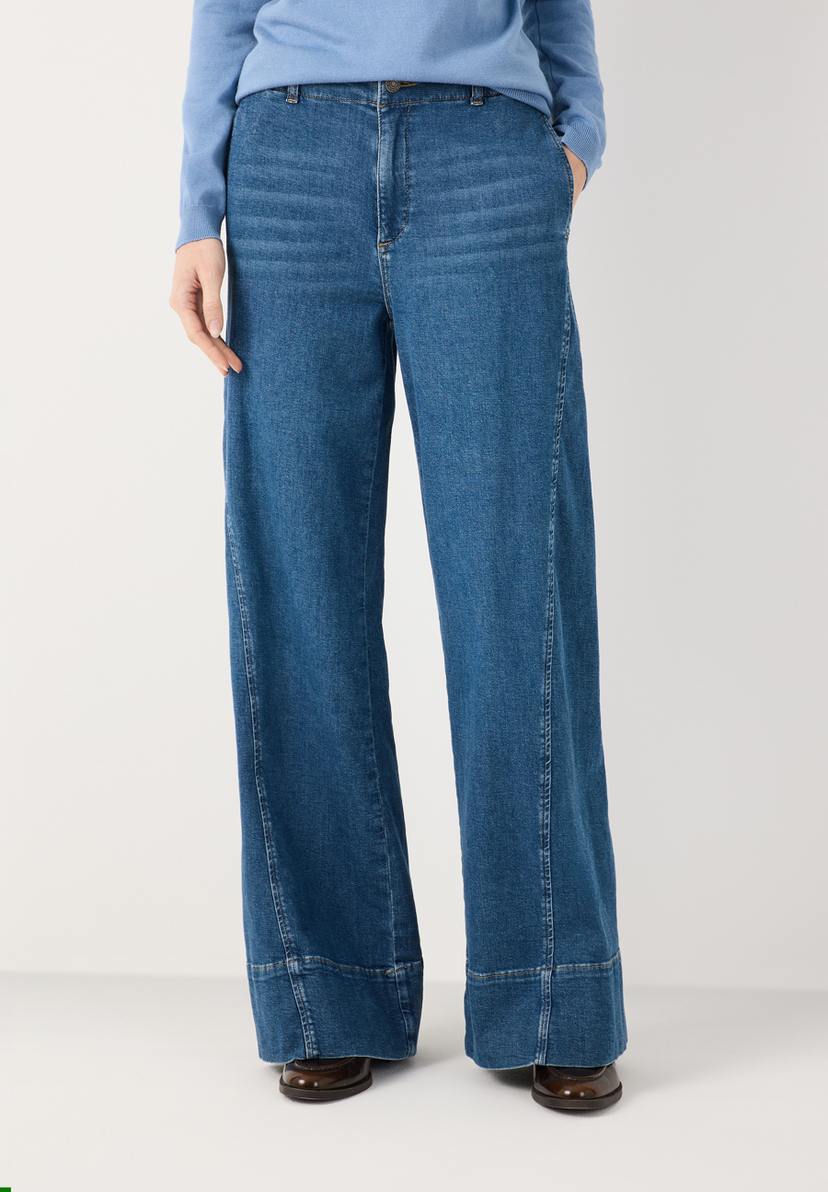 MORE & MORE Damen-Jeans in Dunkelblau, ausgestellter Schnitt. Eine Hand steckt lässig in der Hosentasche.