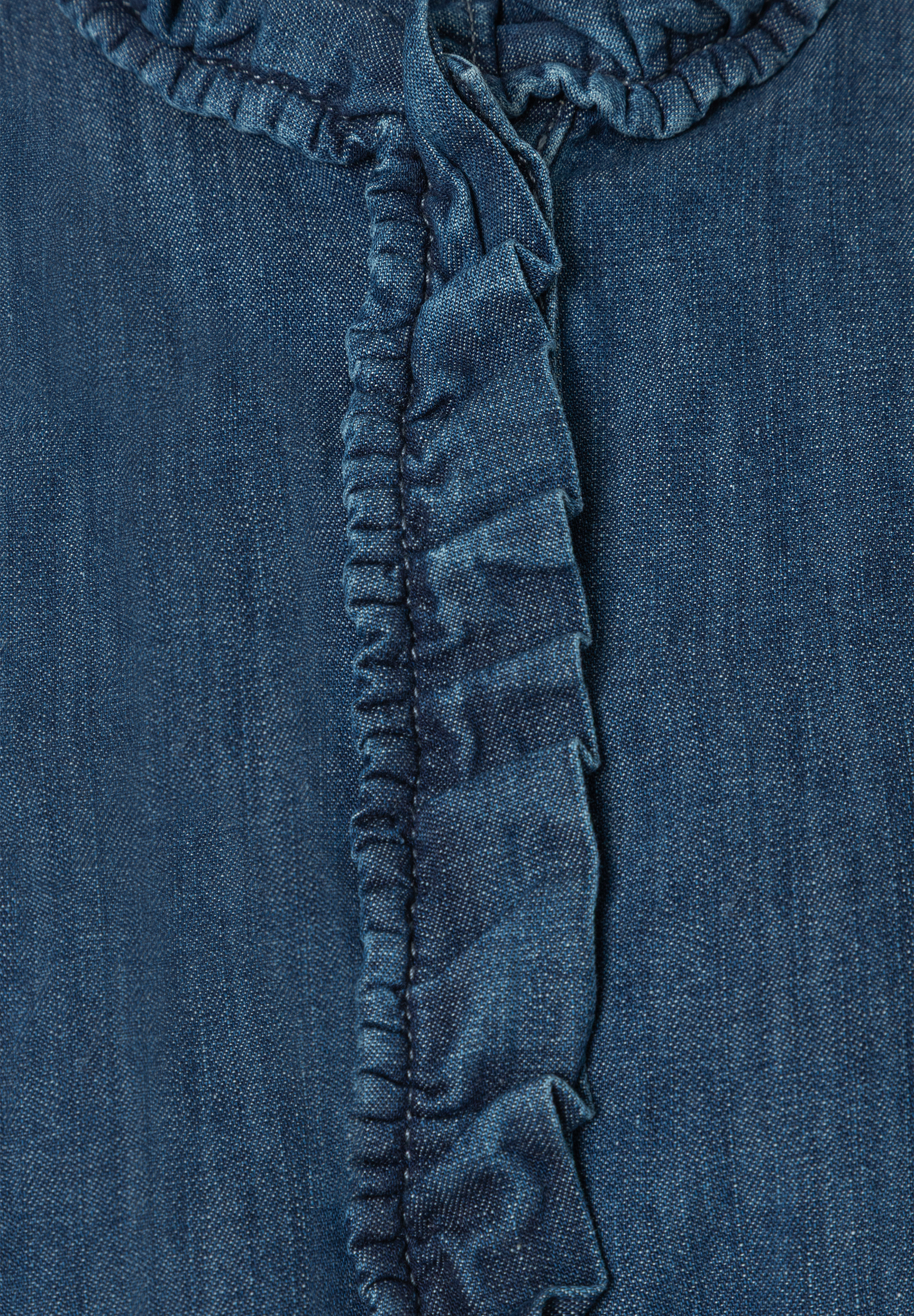 Detailaufnahme einer blauen MORE & MORE Bluse mit Rüschen. Detailaufnahme einer blauen MORE & MORE Bluse mit Rüschen.