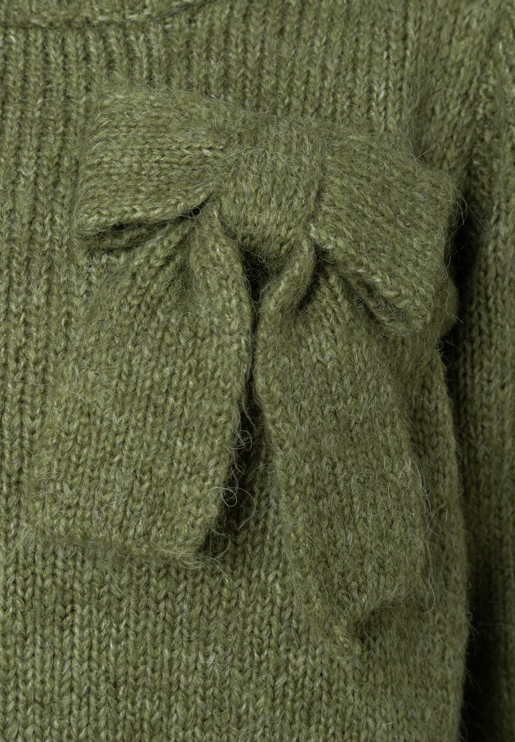Nahaufnahme eines grünen MORE & MORE Strick-Pullovers mit einer dekorativen Schleife. Nahaufnahme eines grünen MORE & MORE Strick-Pullovers mit einer dekorativen Schleife.
