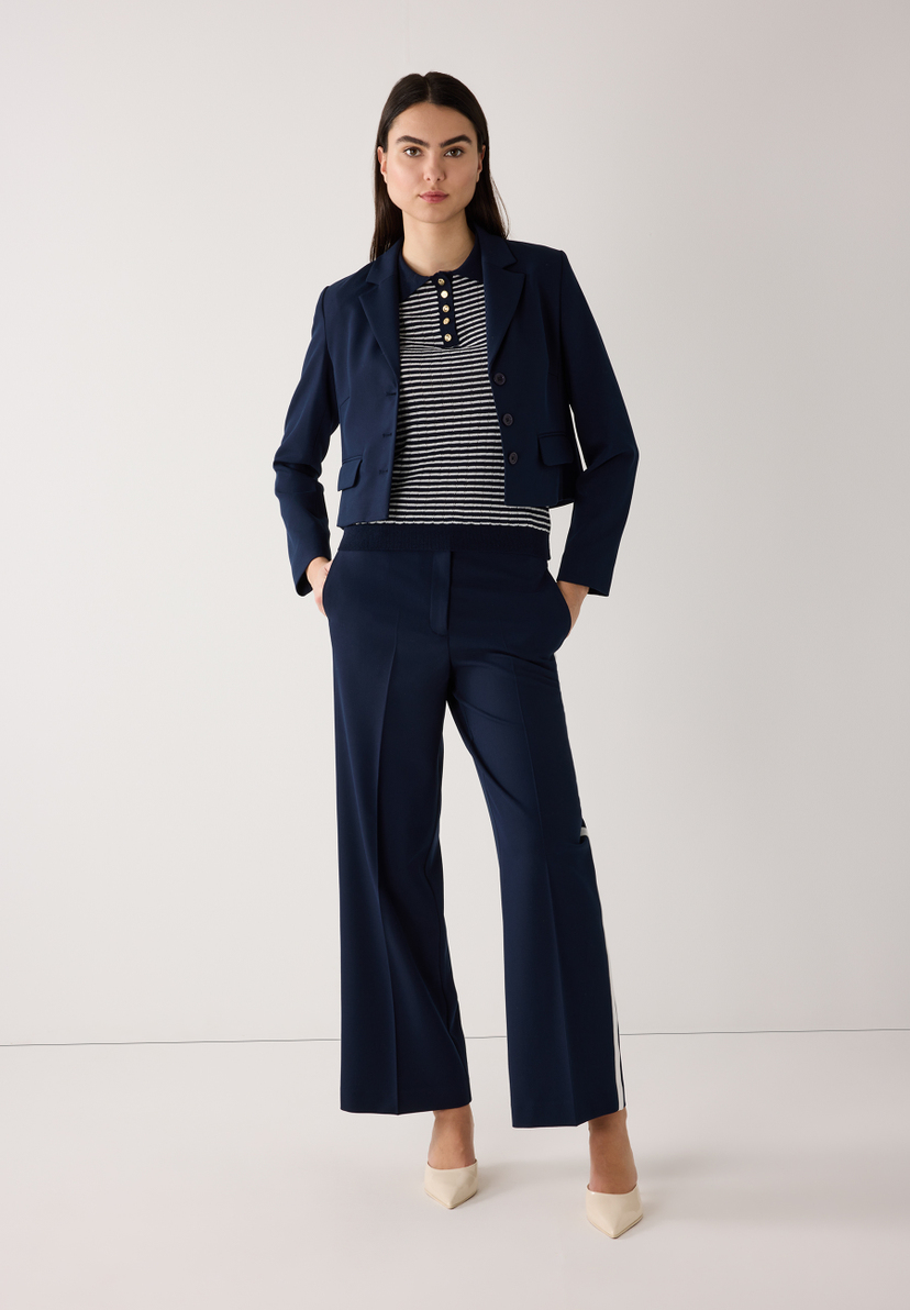 Eine Frau in einem marineblauen MORE & MORE Blazer und passender Hose. Eine Frau in einem marineblauen MORE & MORE Blazer und passender Hose.