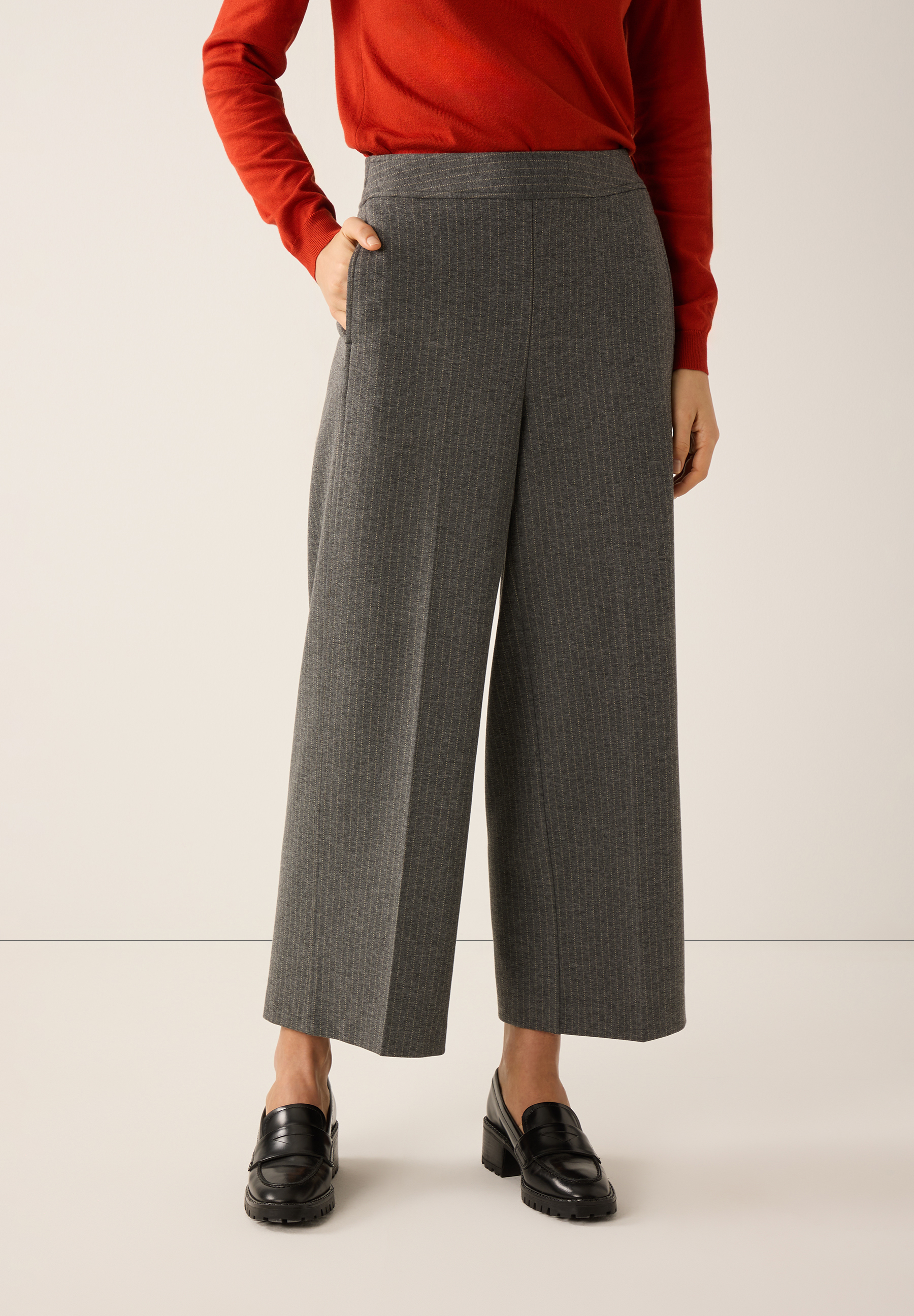 Eine Person trägt eine graue MORE & MORE Webware Hose mit Nadelstreifen und schwarze Schuhe. Eine Person trägt eine graue MORE & MORE Webware Hose mit Nadelstreifen und schwarze Schuhe.