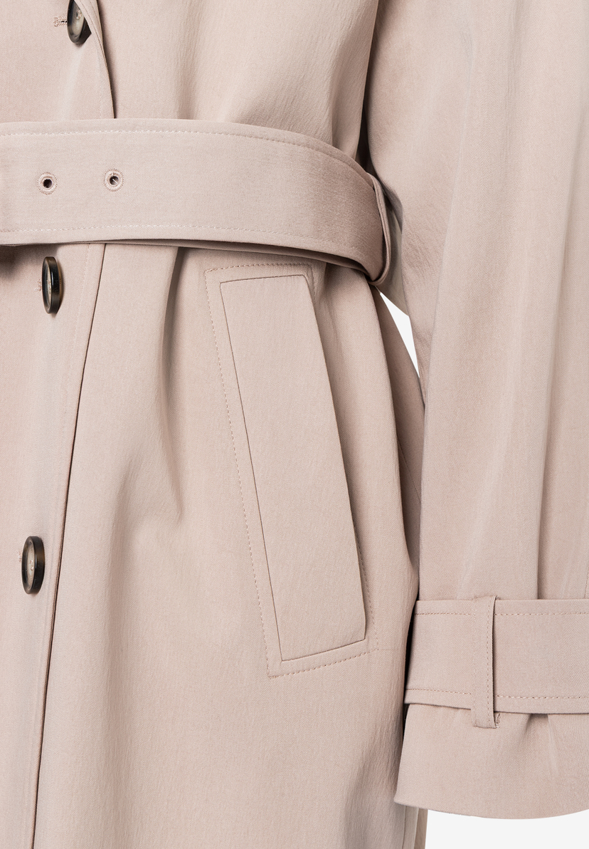 Detailaufnahme eines MORE & MORE Oberteils, das eine Gürtelschnalle, eine aufgesetzte Tasche und Knöpfe zeigt.