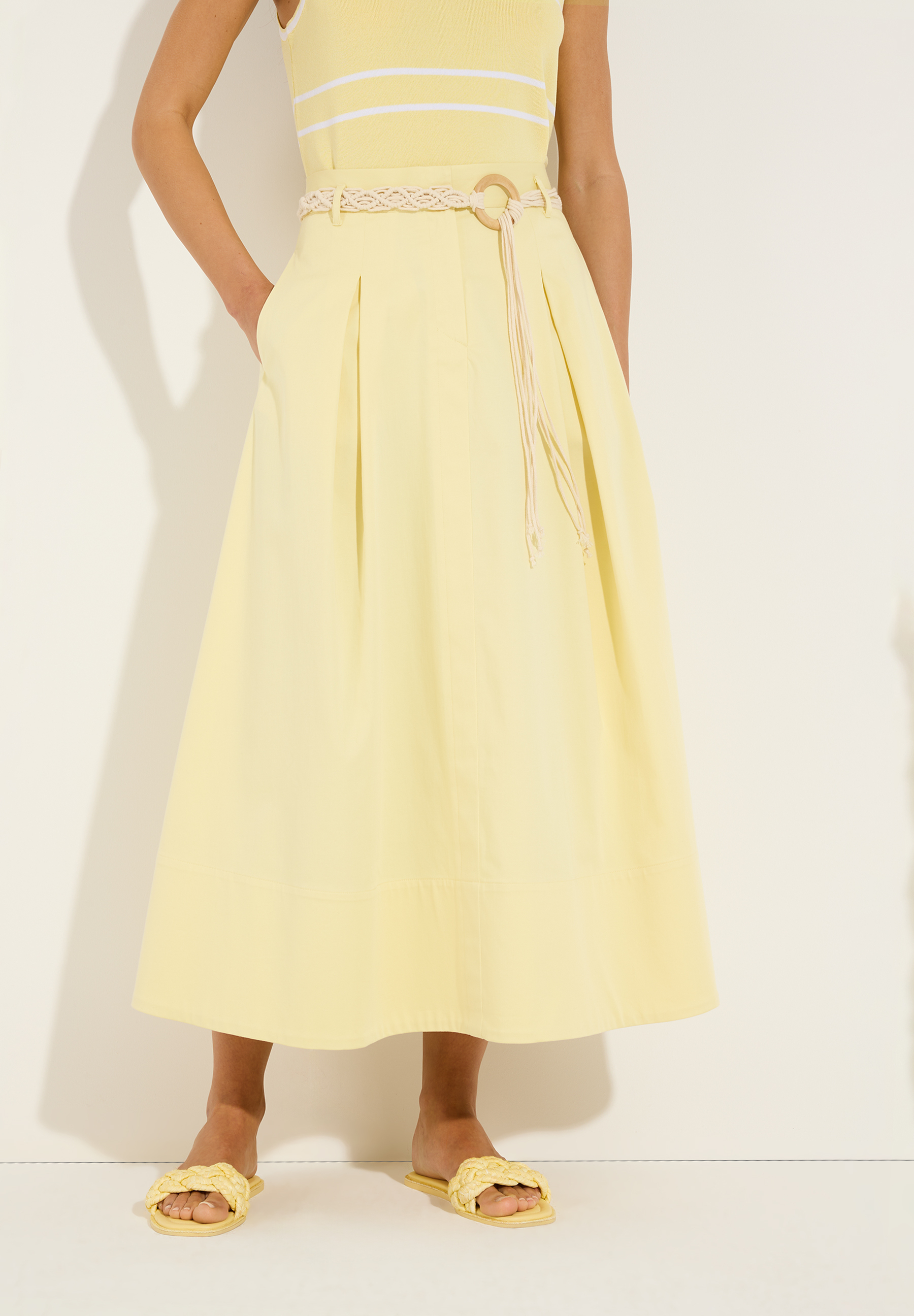 MORE & MORE Midi-Rock in Gelb mit beigem Gürtel und gelben Sandalen auf weißem Hintergrund.