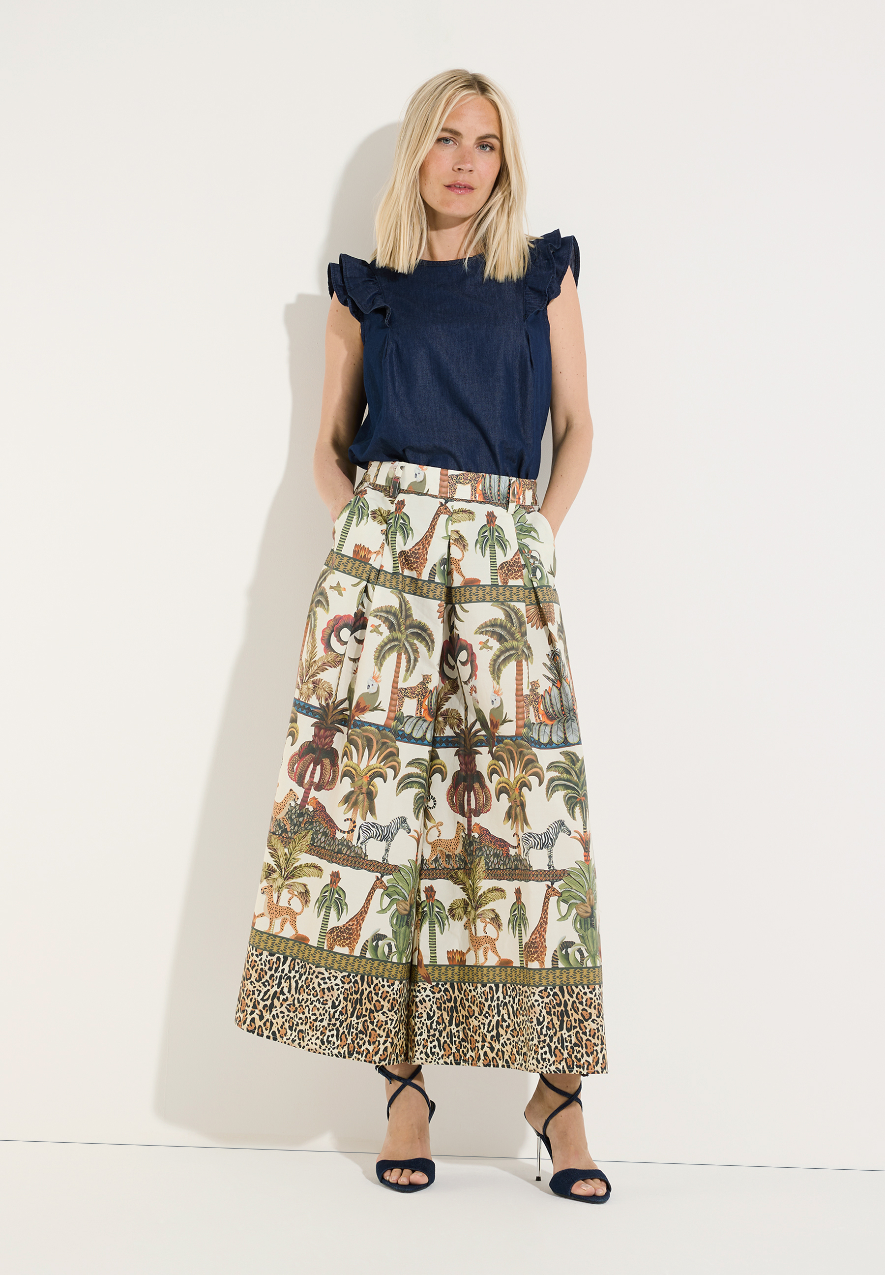 MORE & MORE Jeans: Blonde Frau trägt lässige Jeans mit Dschungel-Print, Leopardenmuster und High Heels. MORE & MORE Jeans: Blonde Frau trägt lässige Jeans mit Dschungel-Print, Leopardenmuster und High Heels.