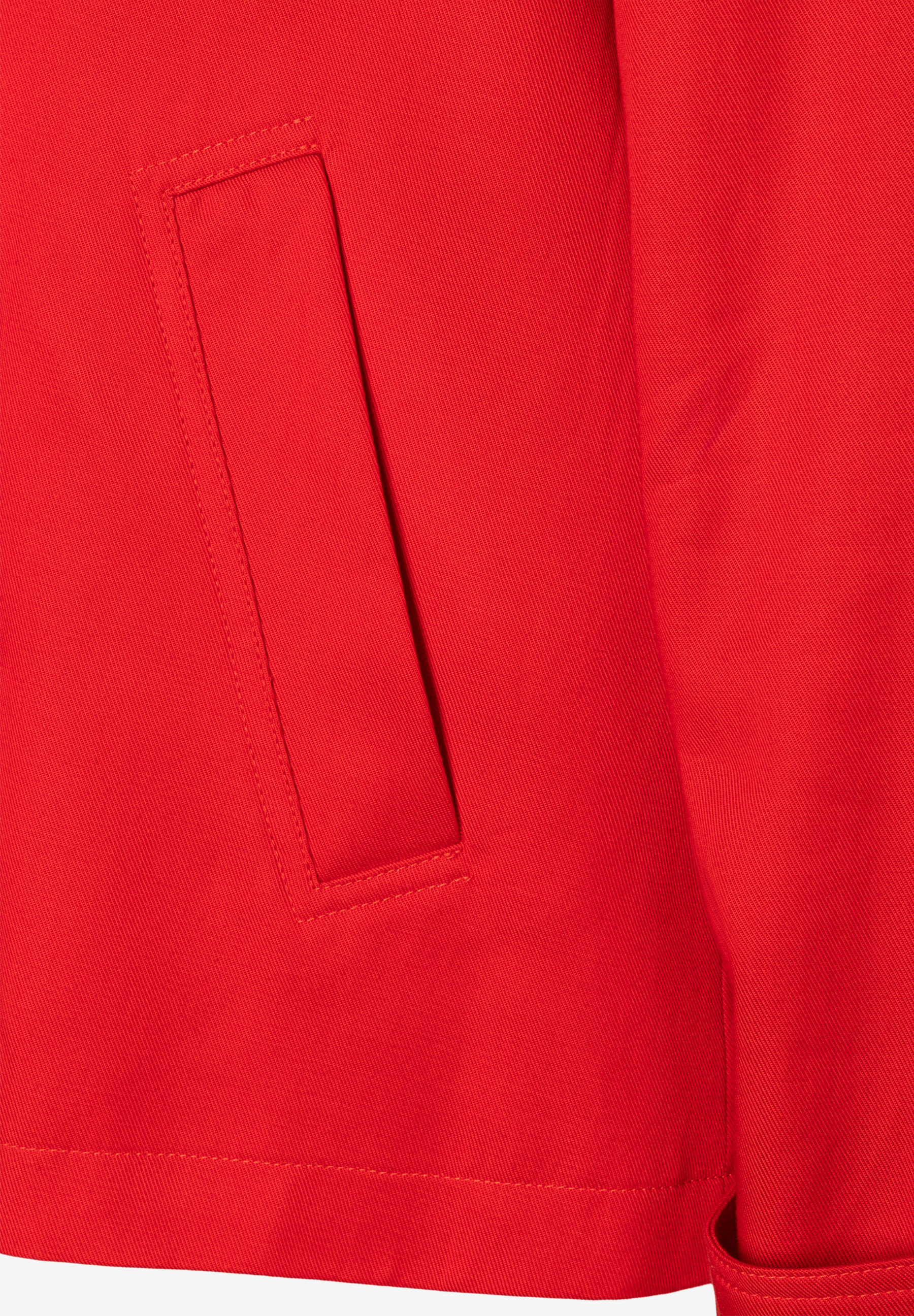 Detail einer roten MORE & MORE Jacke aus Twill mit aufgesetzter Tasche. Detail einer roten MORE & MORE Jacke aus Twill mit aufgesetzter Tasche.