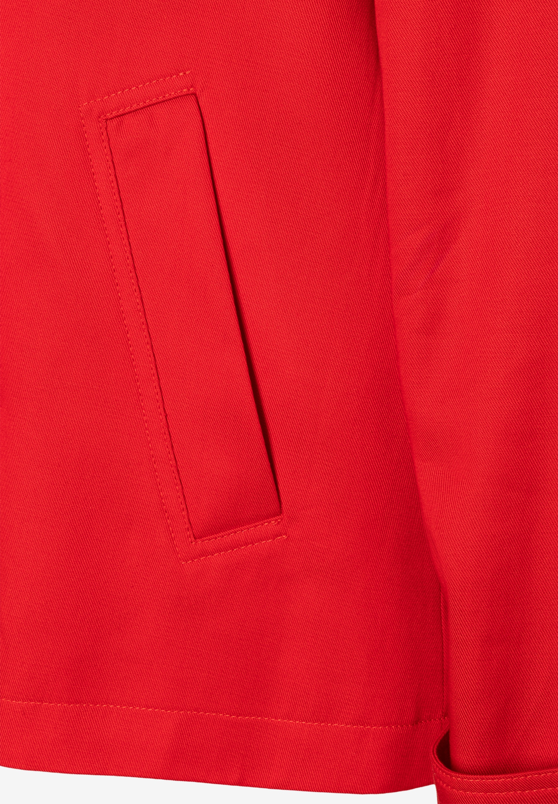 Detail einer roten MORE & MORE Jacke aus Twill mit aufgesetzter Tasche. Detail einer roten MORE & MORE Jacke aus Twill mit aufgesetzter Tasche.