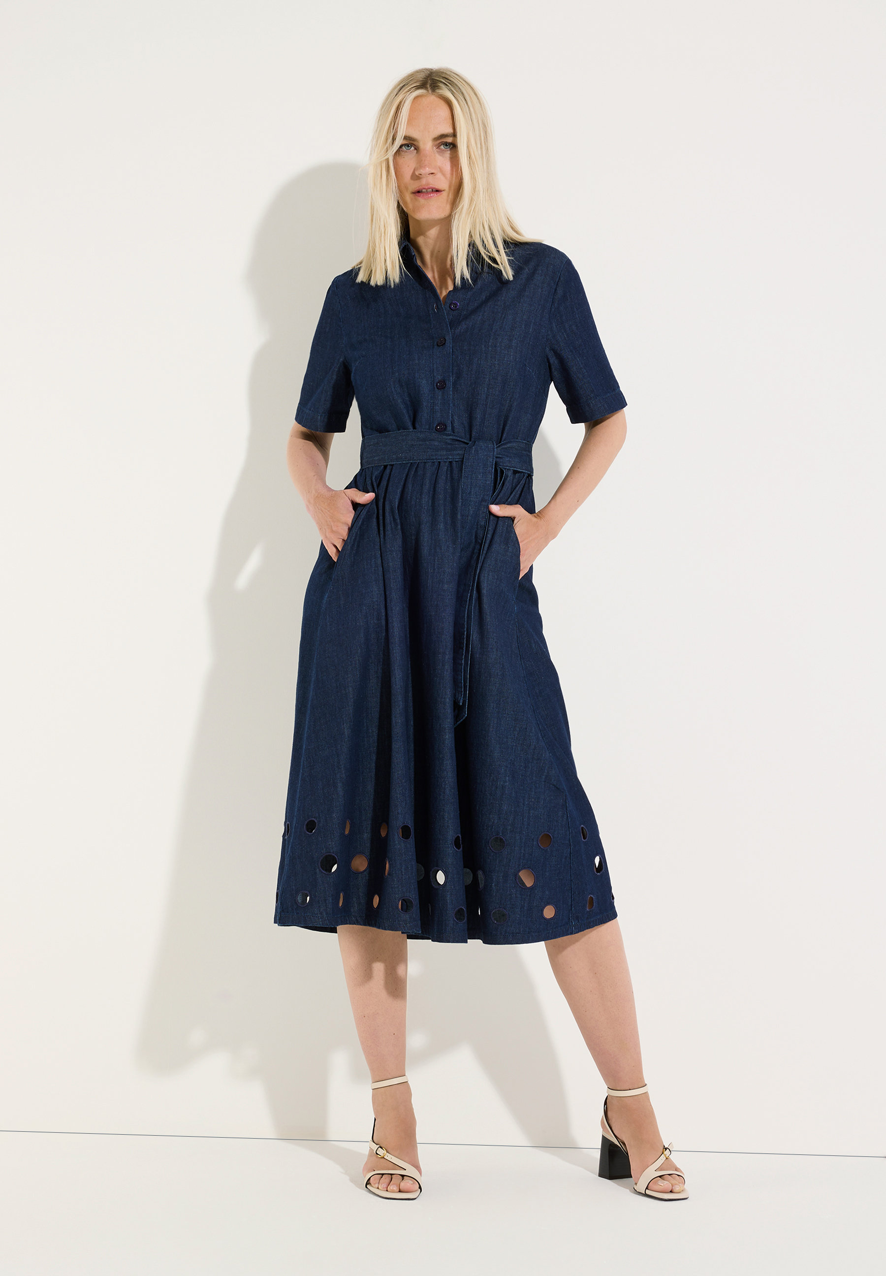 MORE & MORE Denim-Kleid in Dunkelblau mit Cut-Outs am Saum und Bindegürtel, getragen von einer blonden Frau vor weißem Hintergrund.