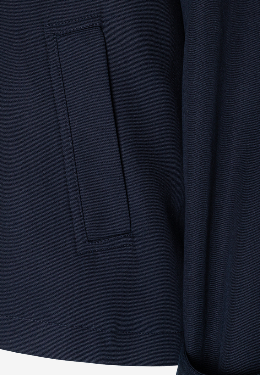 Nahaufnahme einer dunkelblauen MORE & MORE Twill-Jacke mit einer eingesetzten Tasche. Nahaufnahme einer dunkelblauen MORE & MORE Twill-Jacke mit einer eingesetzten Tasche.