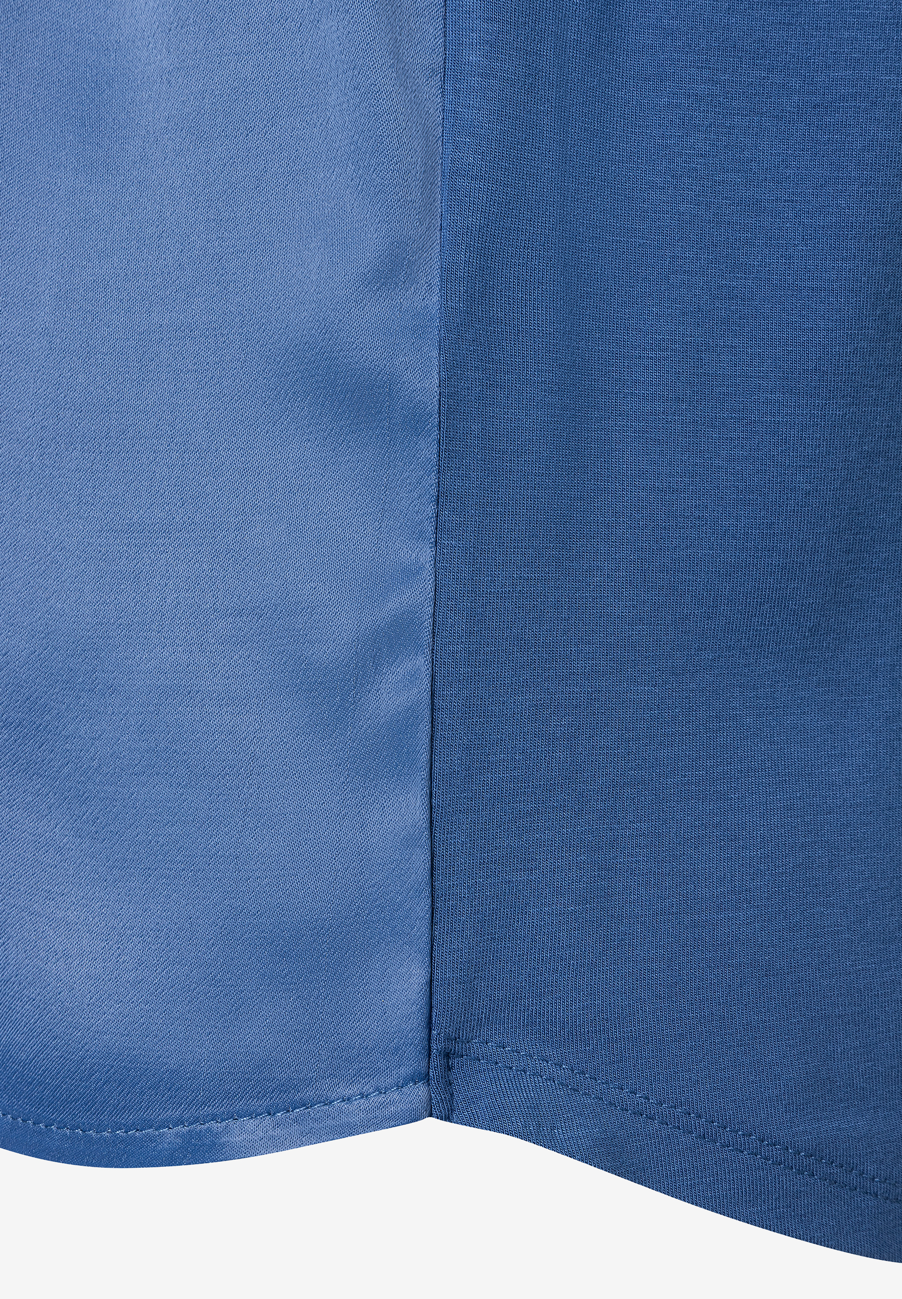 Nahaufnahme eines blauen MORE & MORE Oberteils mit Naht und unterschiedlichen Stoffstrukturen. Nahaufnahme eines blauen MORE & MORE Oberteils mit Naht und unterschiedlichen Stoffstrukturen.