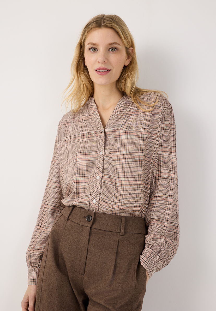 MORE & MORE Bluse: Eine junge Frau trägt eine karierte Bluse und braune Hose, die Hände in den Hosentaschen. MORE & MORE Bluse: Eine junge Frau trägt eine karierte Bluse und braune Hose, die Hände in den Hosentaschen.