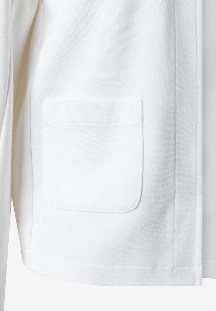 Detailaufnahme eines weißen MORE & MORE Tops mit einer aufgesetzten Tasche.