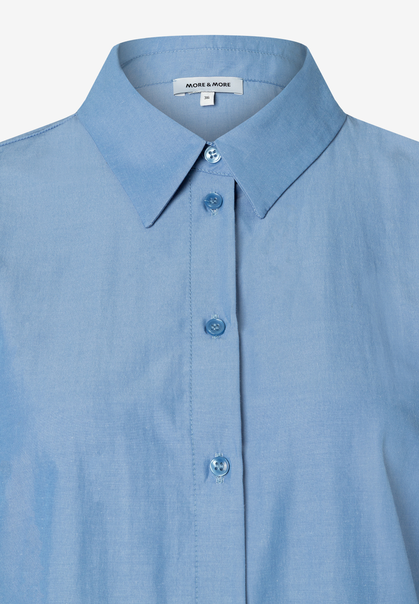 Nahaufnahme einer hellblauen MORE & MORE Bluse aus elastischer Popeline mit Kragen und Knopfleiste. Nahaufnahme einer hellblauen MORE & MORE Bluse aus elastischer Popeline mit Kragen und Knopfleiste.