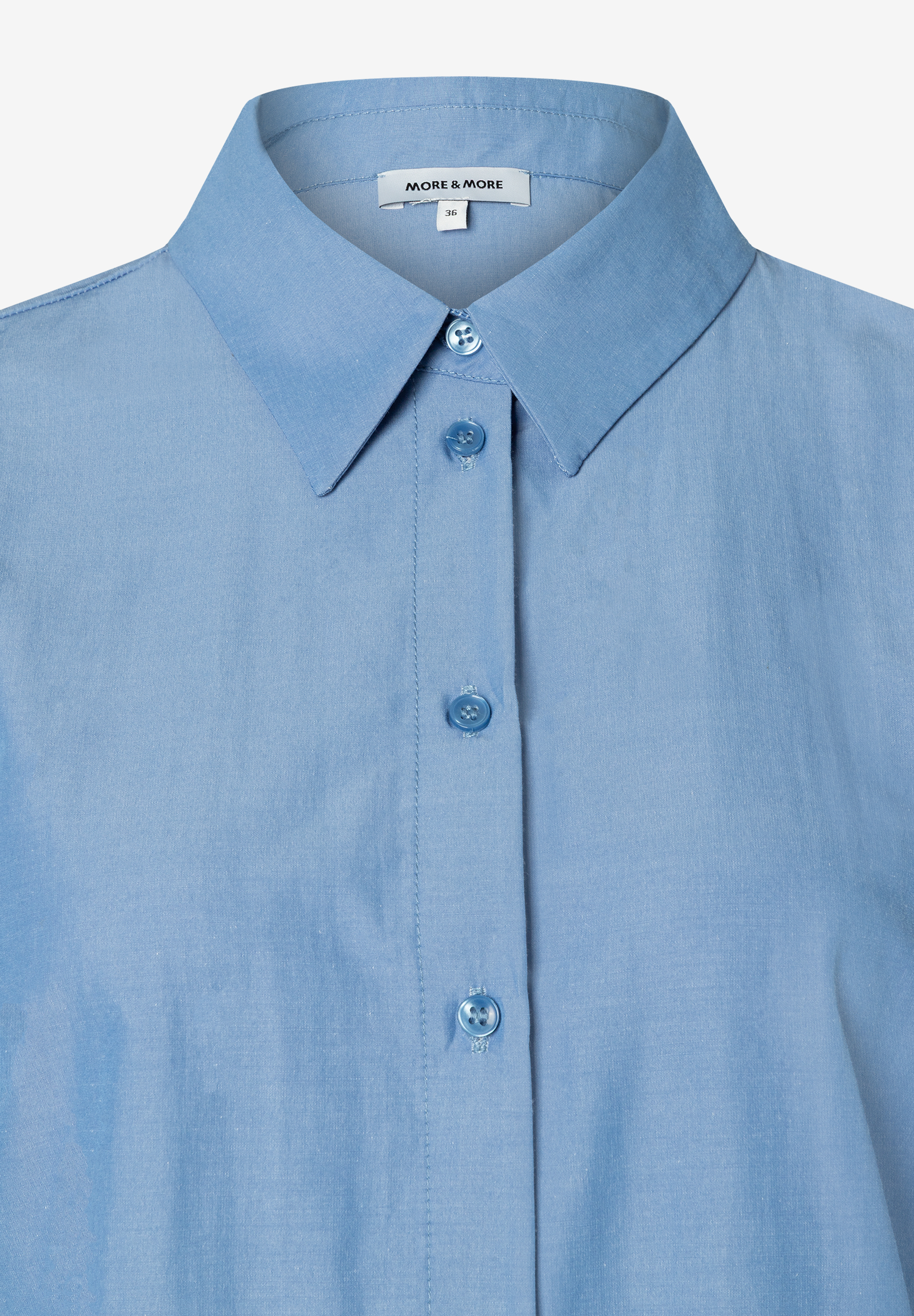 Nahaufnahme einer hellblauen MORE & MORE Bluse aus elastischer Popeline mit Kragen und Knopfleiste. Nahaufnahme einer hellblauen MORE & MORE Bluse aus elastischer Popeline mit Kragen und Knopfleiste.