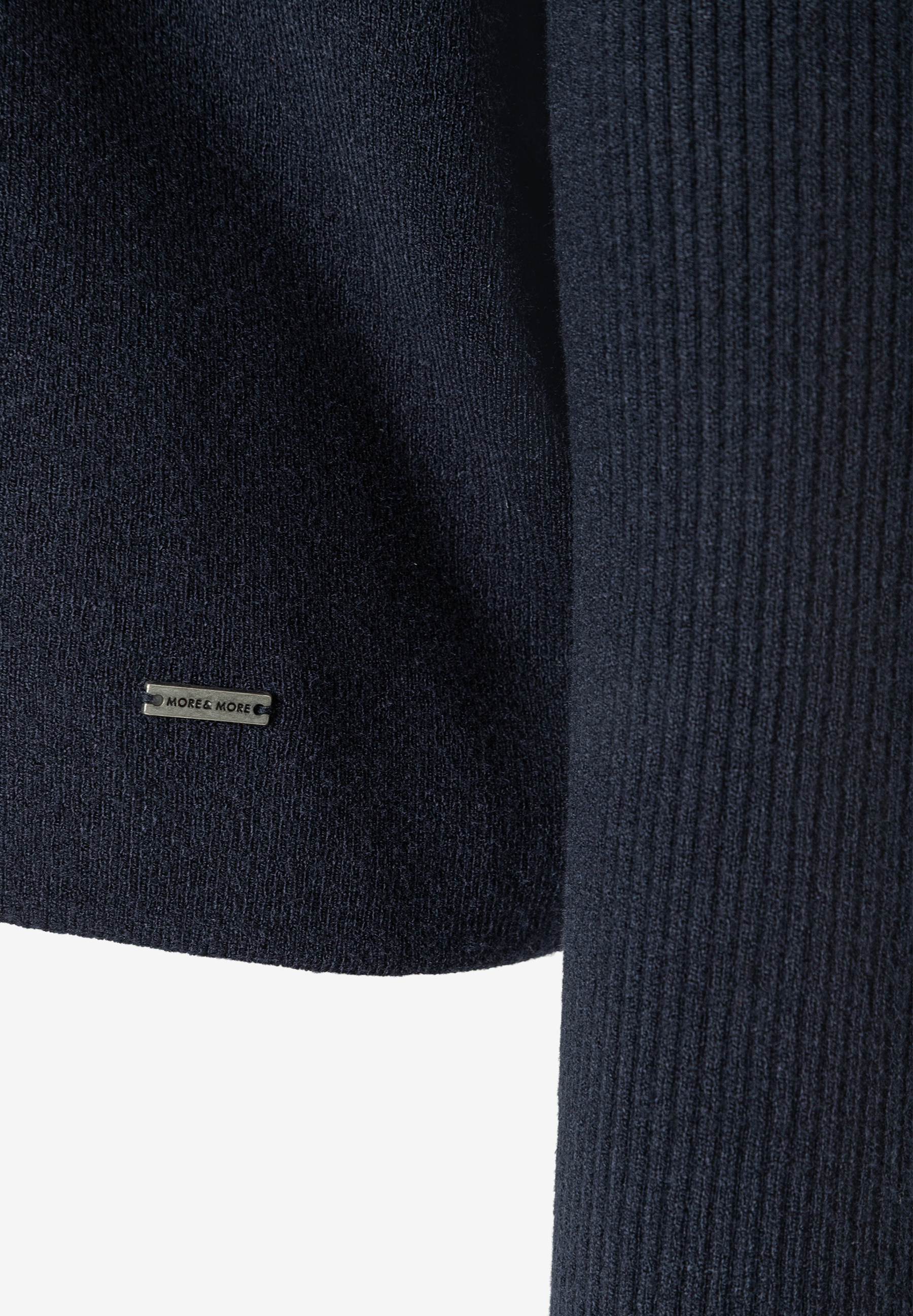 MORE & MORE Rippstrick-Pullover in Marineblau, Nahaufnahme des Saums mit Markenetikett und geripptem Ärmel