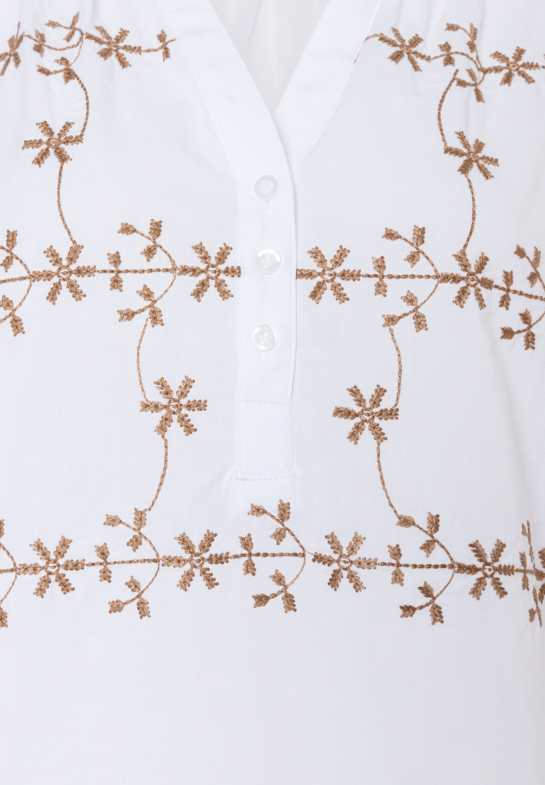 Nahaufnahme einer weißen MORE & MORE Bluse mit Knopfleiste und floralen Stickereien in Gold. Nahaufnahme einer weißen MORE & MORE Bluse mit Knopfleiste und floralen Stickereien in Gold.