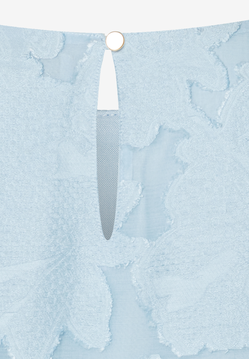 Detailaufnahme einer hellblauen MORE & MORE Bluse. Blickfang: goldener Knopf über tropfenförmigem Ausschnitt. Detailaufnahme einer hellblauen MORE & MORE Bluse. Blickfang: goldener Knopf über tropfenförmigem Ausschnitt.